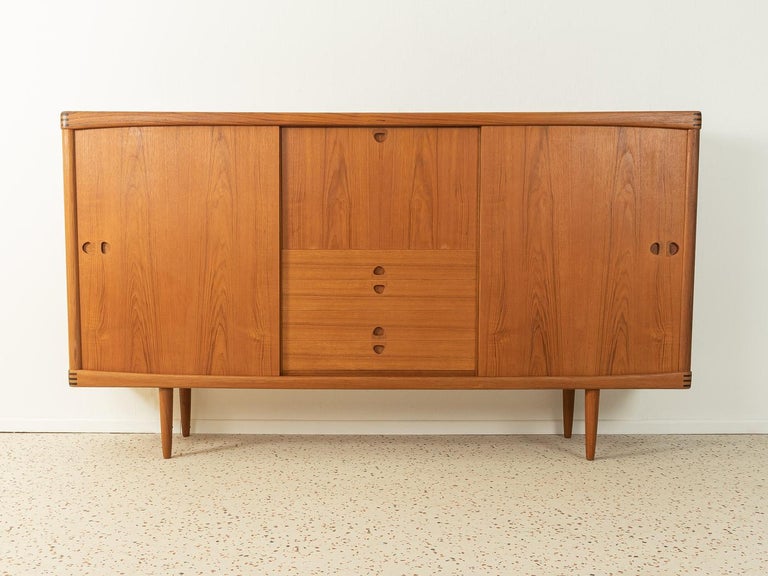 Classic highboard from the 1960s. High quality corpus in teak veneer with two sliding doors, four drawers, a hinged compartment, seven shelves and cigar shaped feet.

Quality Features:
- accomplished design: perfect proportions and visible