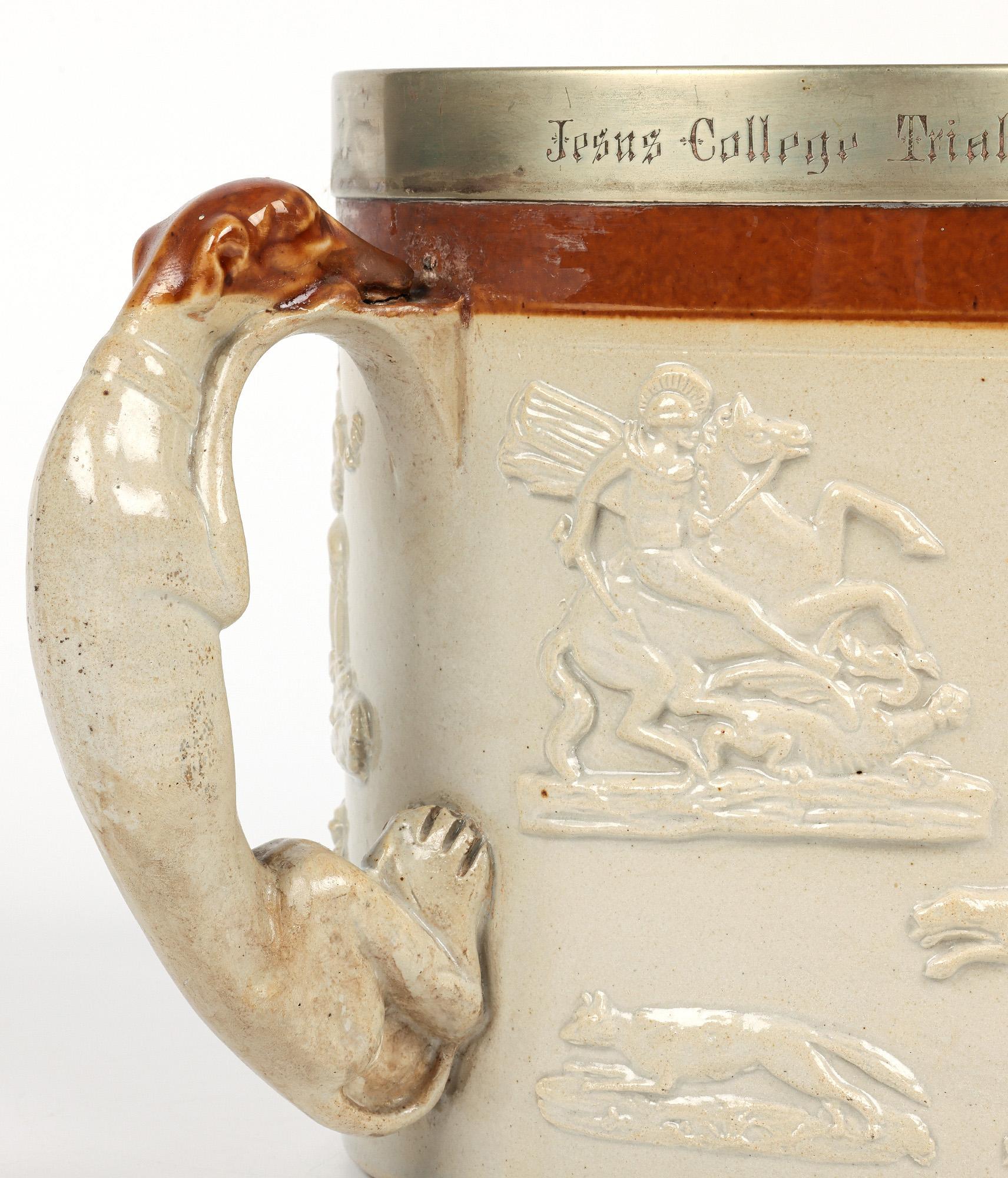 A large and impressive Jesus College, Cambridge University Rowing Presentation salt glazed pottery tyg by Brampton dated 1869. The large stoneware tyg is of cylindrical shape standing on a flat round base and is applied with three large molded grey