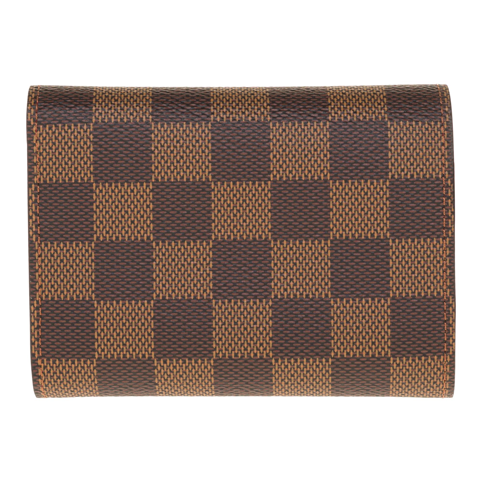 Crafted in Damier Ébène canvas, this compact Victorine wallet is distinguished by its flap silhouette. Its interior reveals many details such as a storage space for bills and cards as well as a side pocket with zipper for currency. This model owes