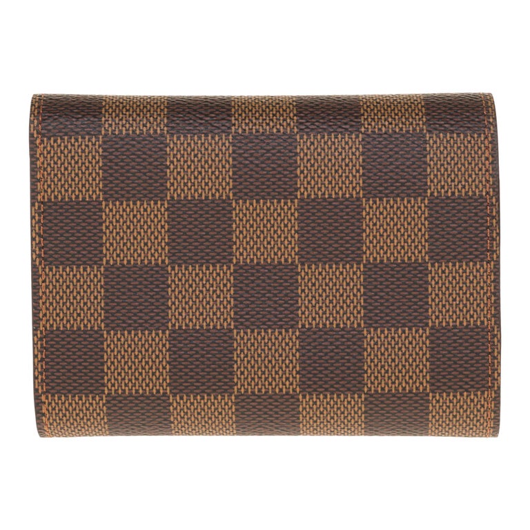 Crafted in Damier Ébène canvas, this compact Victorine wallet is distinguished by its flap silhouette. Its interior reveals many details such as a storage space for bills and cards as well as a side pocket with zipper for currency. This model owes
