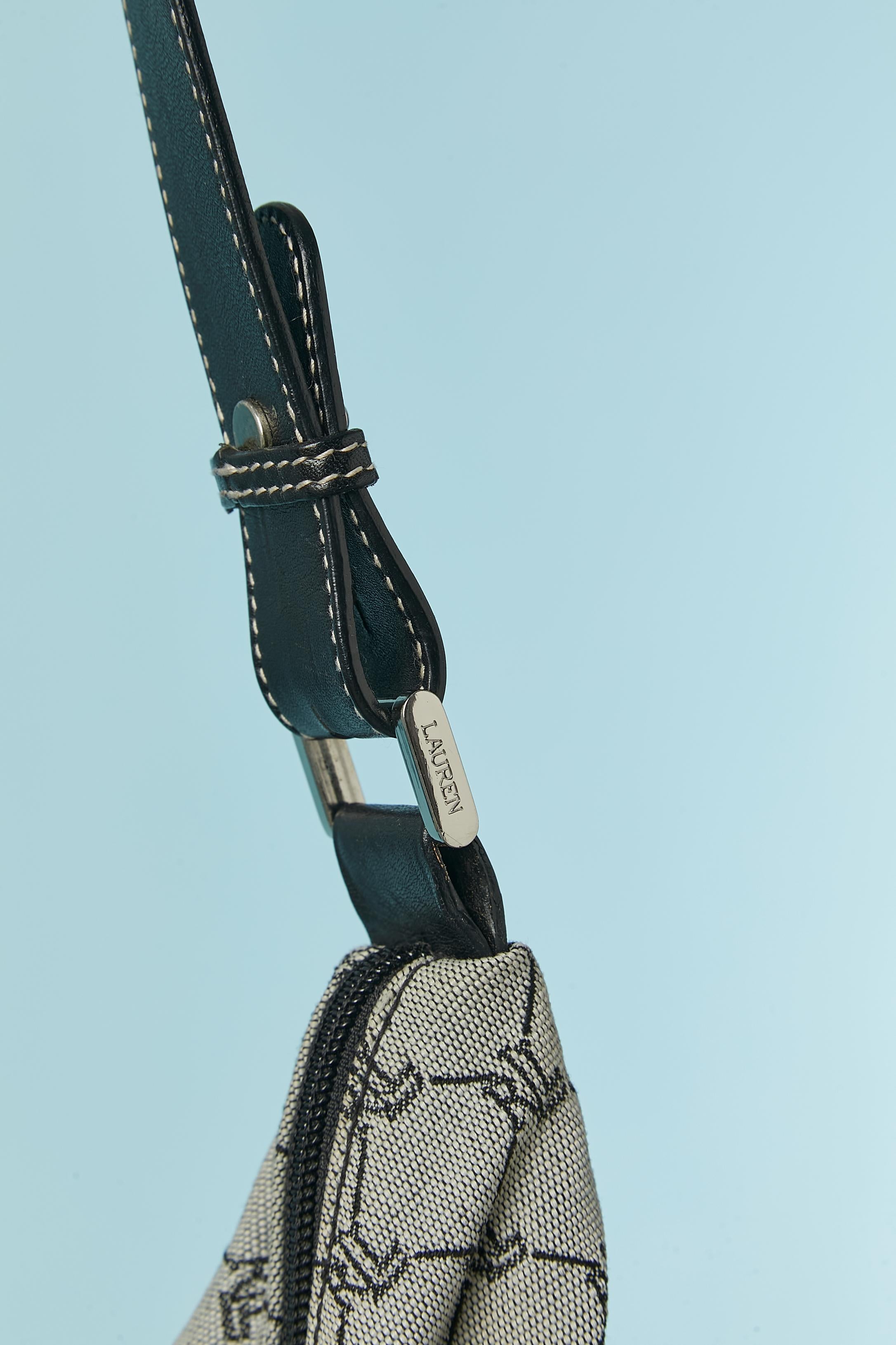 Bolso bandolera canevas de marca con correa de piel ajustable. Forro de nylon (¿o poliéster?) de marca. Cierre de cremallera en la parte superior del bolso con tirador de cremallera de piel de la marca. 
 Un bolsillo interior con cierre de