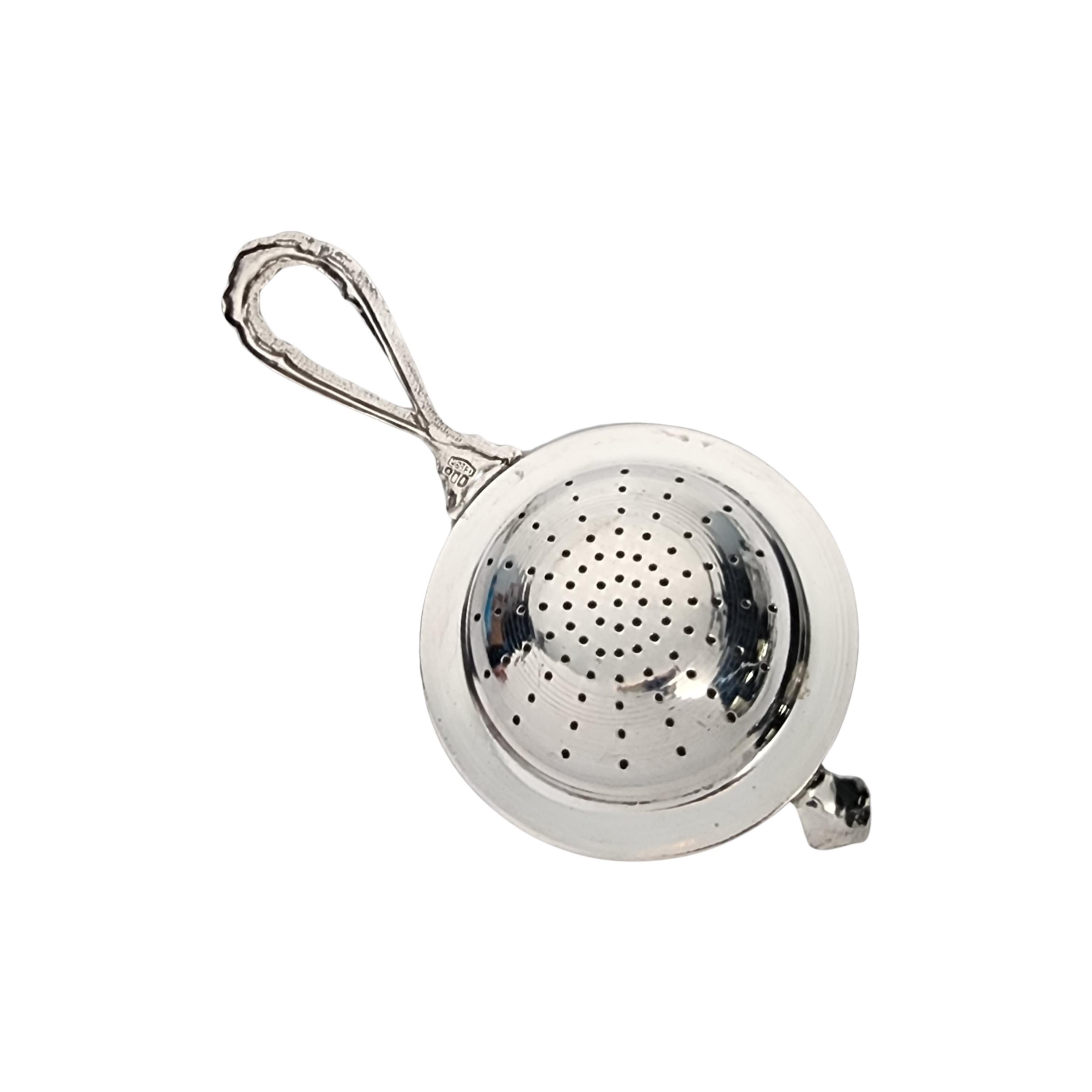 Vintage 800 silver tea strainer by Brandimarte Italy.

This tea strainer features an open loop design handle topped with a rose, and a rope edge design around the pierced bowl.

Measures approx 4 5/8