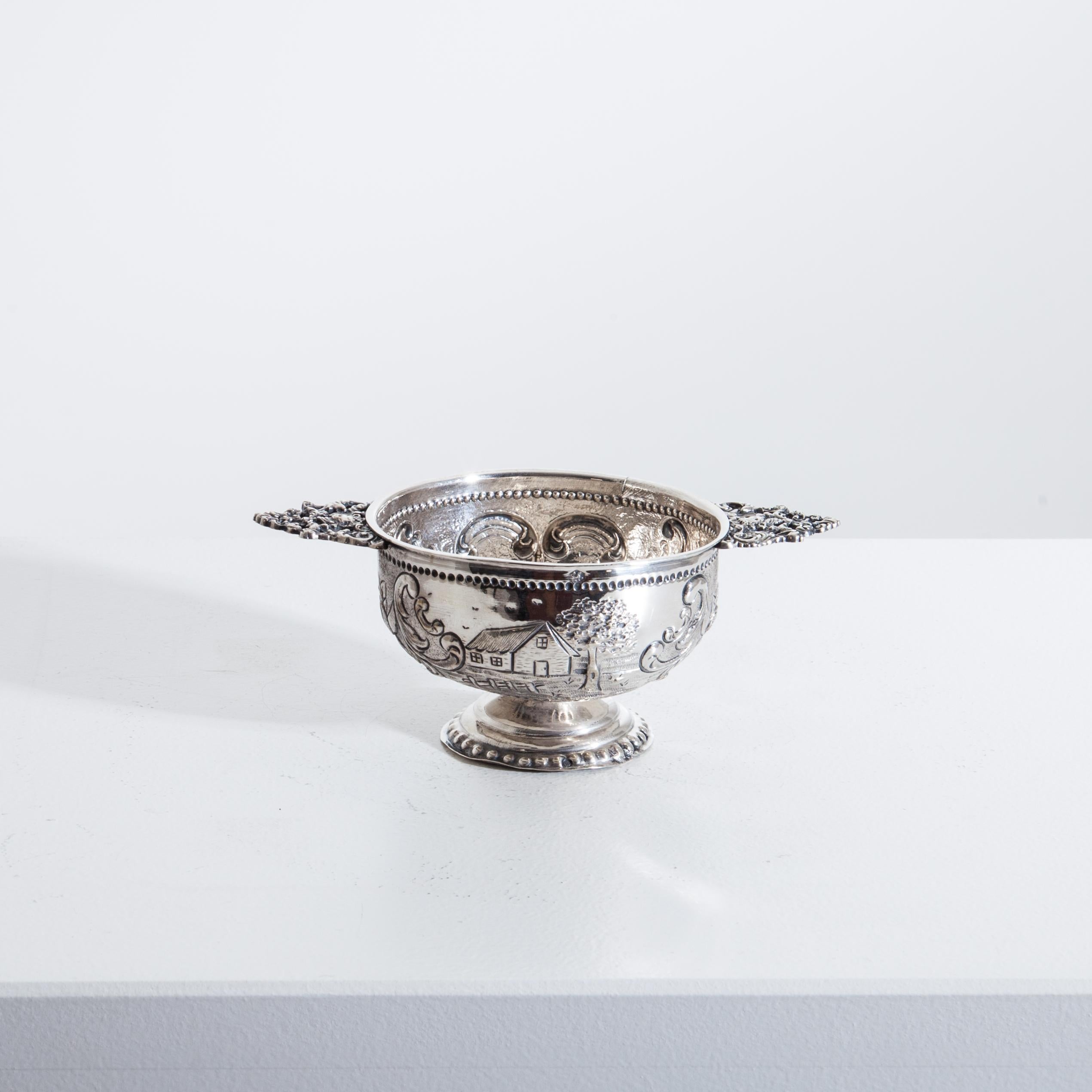 A small silver Renaissance style brandy cup on a round base, with typical flat handles and leaf and rocaille decoration on the wall.