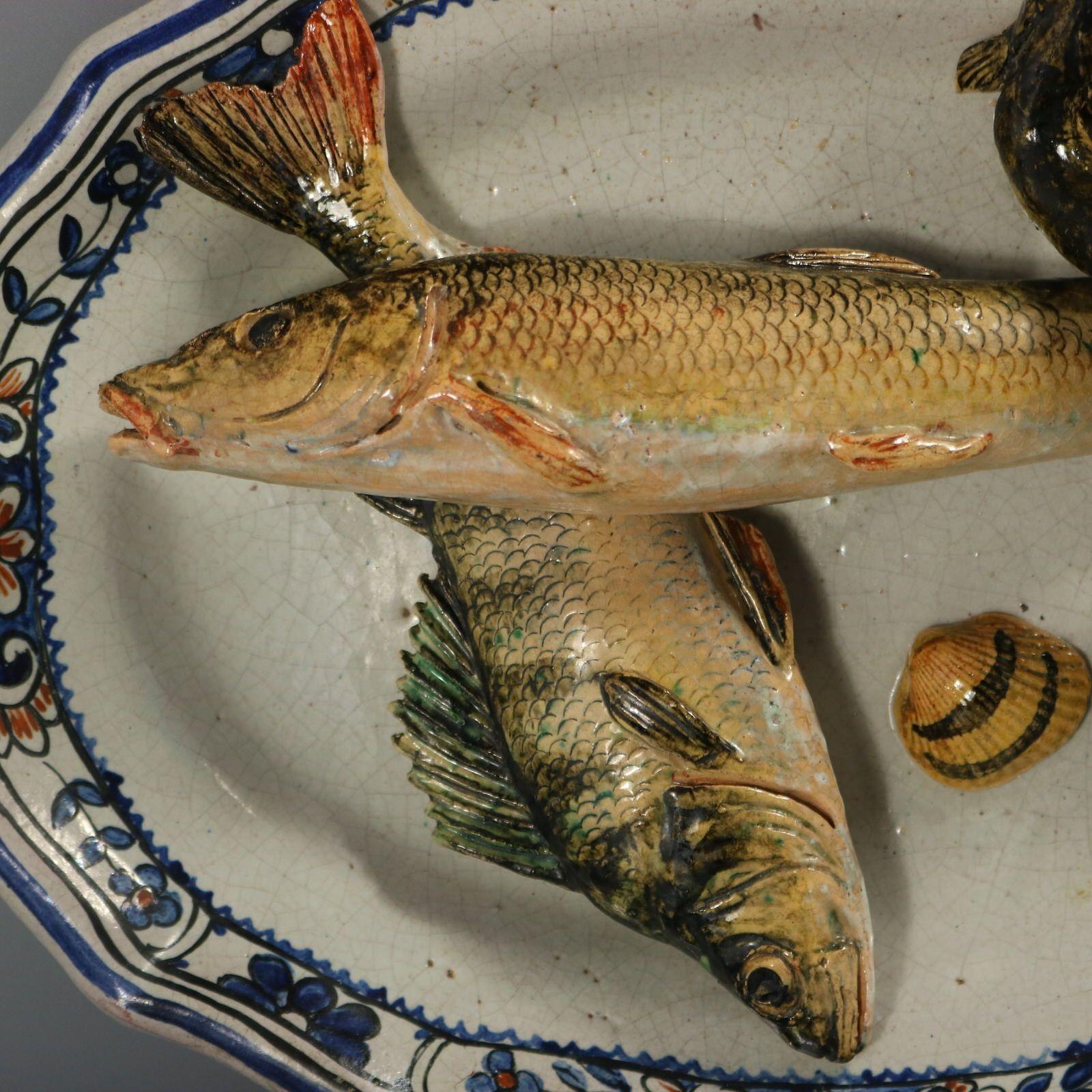 Brard Majolica wall platter which features fish (a perch and a barbel), an eel and a cockle shell. An attractive floral border. Colouration: blue, black, grey, are predominant. The piece bears maker's marks for the Brard pottery.