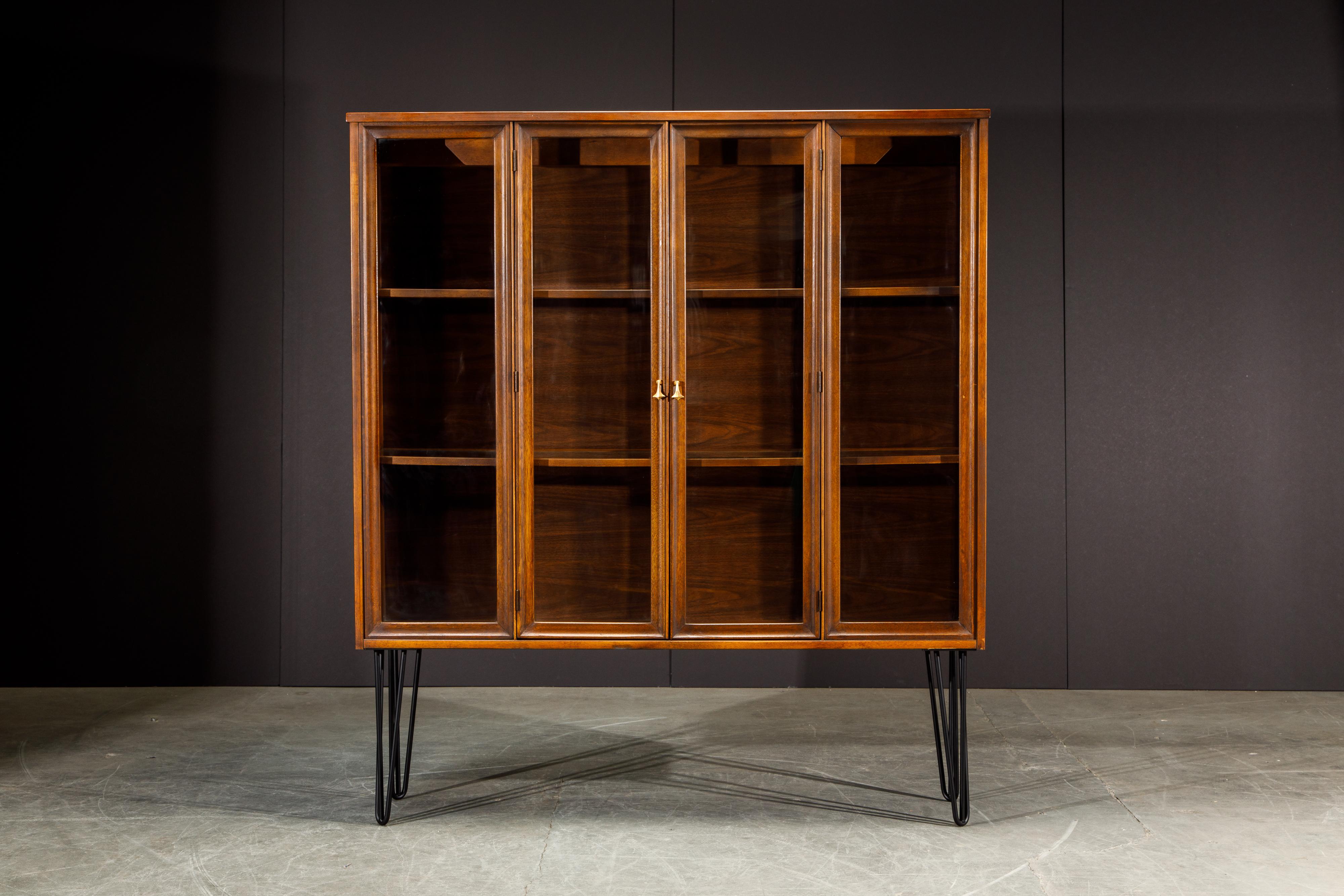 This 1960s 'Brasilia' by Broyhill Premiere display cabinet features gorgeous brass pulls in its signature Brazilia shape with two walnut and glass cabinet doors that open up to interior shelf space and illuminated interior. New hairpin legs were