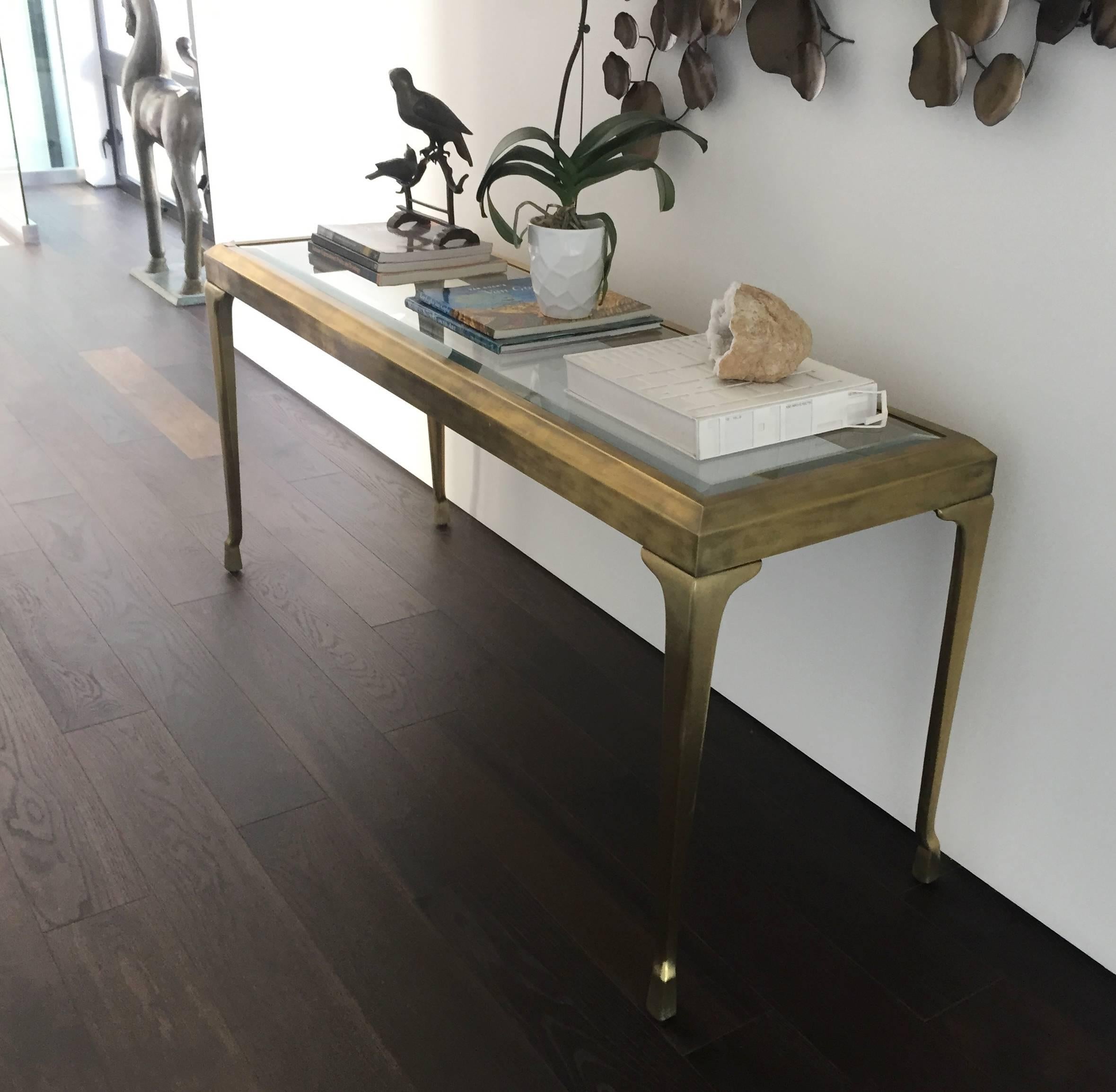 Stunning and beautiful hall or console table in solid brass and glass top designed and manufactured by Mastercraft.
The table has a very nice aged patina and shows very well.
 