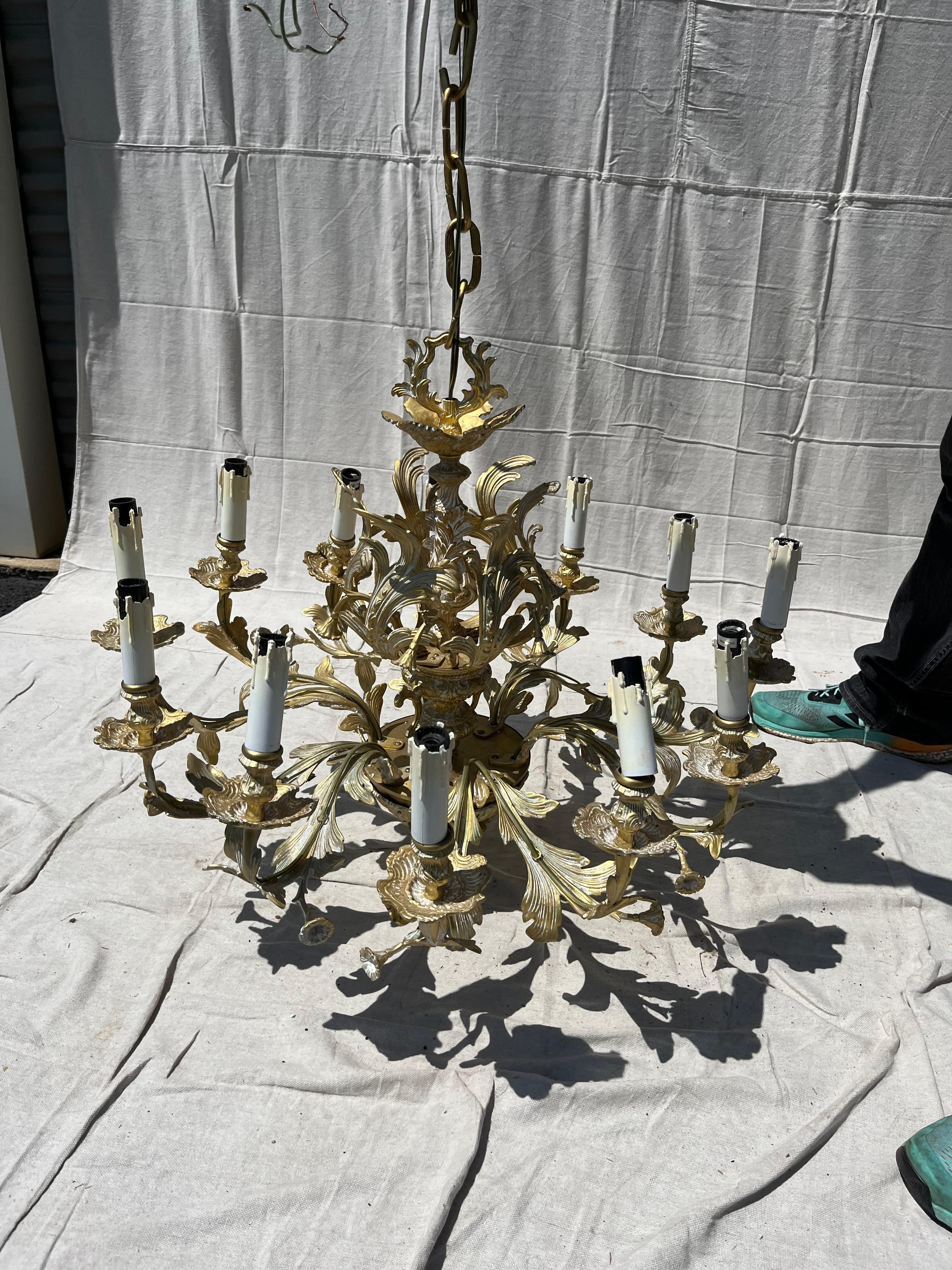 A French style 12-arm brass chandelier with cast leaves and floral decoration.  