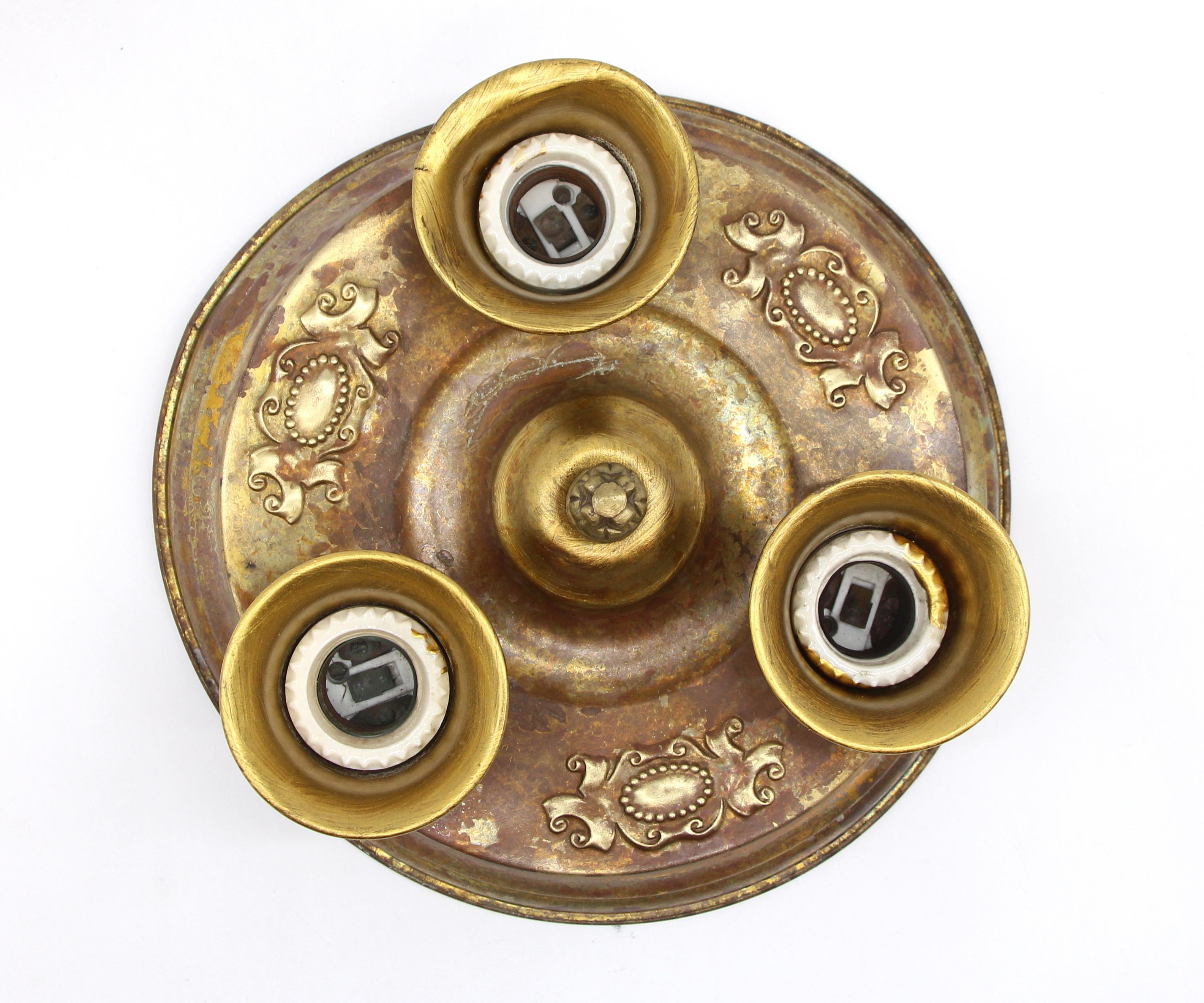 Antique brass ceiling light fixture with three sockets and ornate detail. It is made with pressed brass and dates to around the 1930s. Original patina. This can be seen at our 400 Gilligan St location in Scranton, PA.