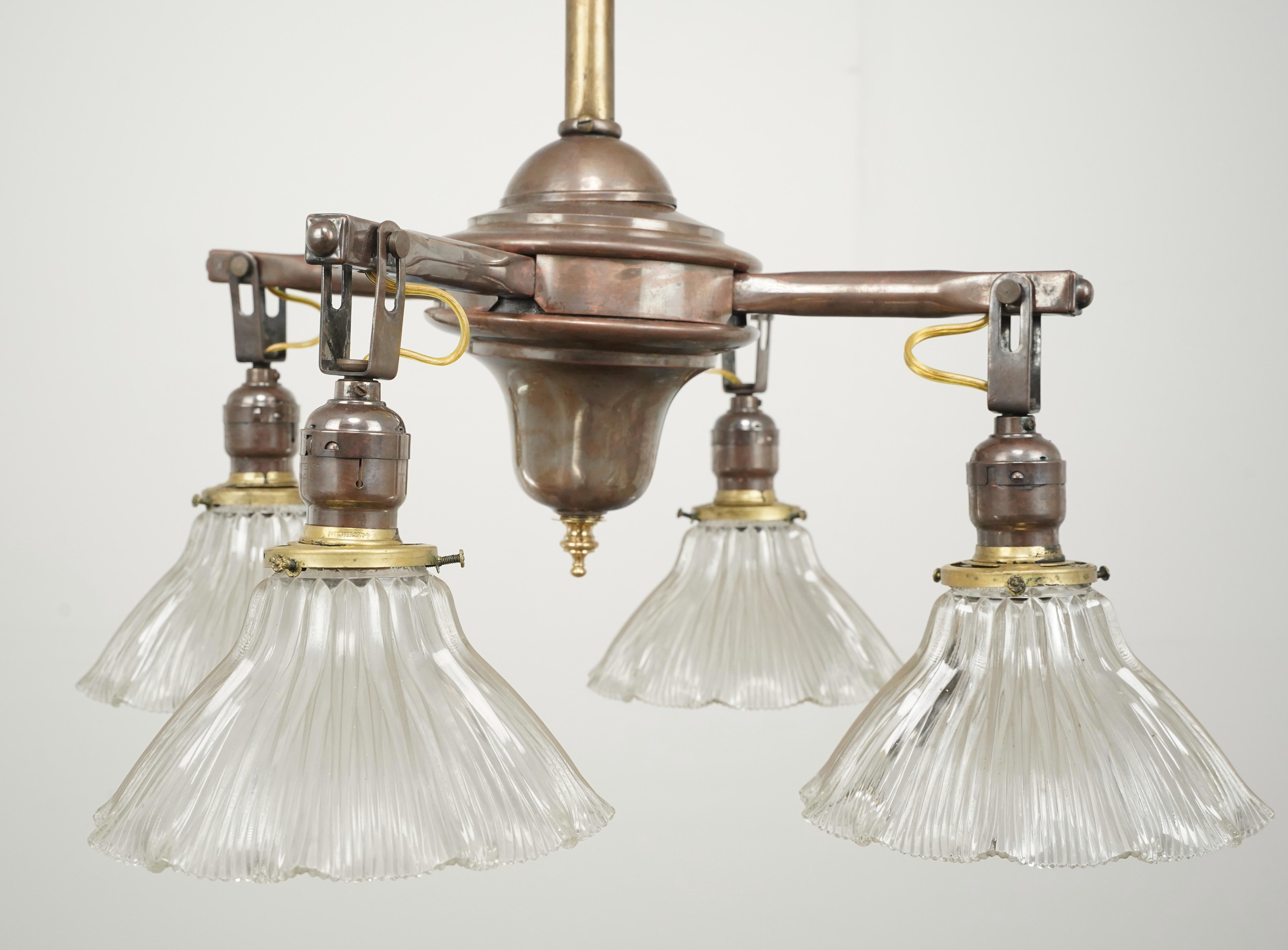 Traditional style chandelier with four arms, with clear glass ruffled shades and an antique brass finish pole. This requires four standard Edison style medium base bulbs. This light is cleaned and restored and ready to ship. Good condition with