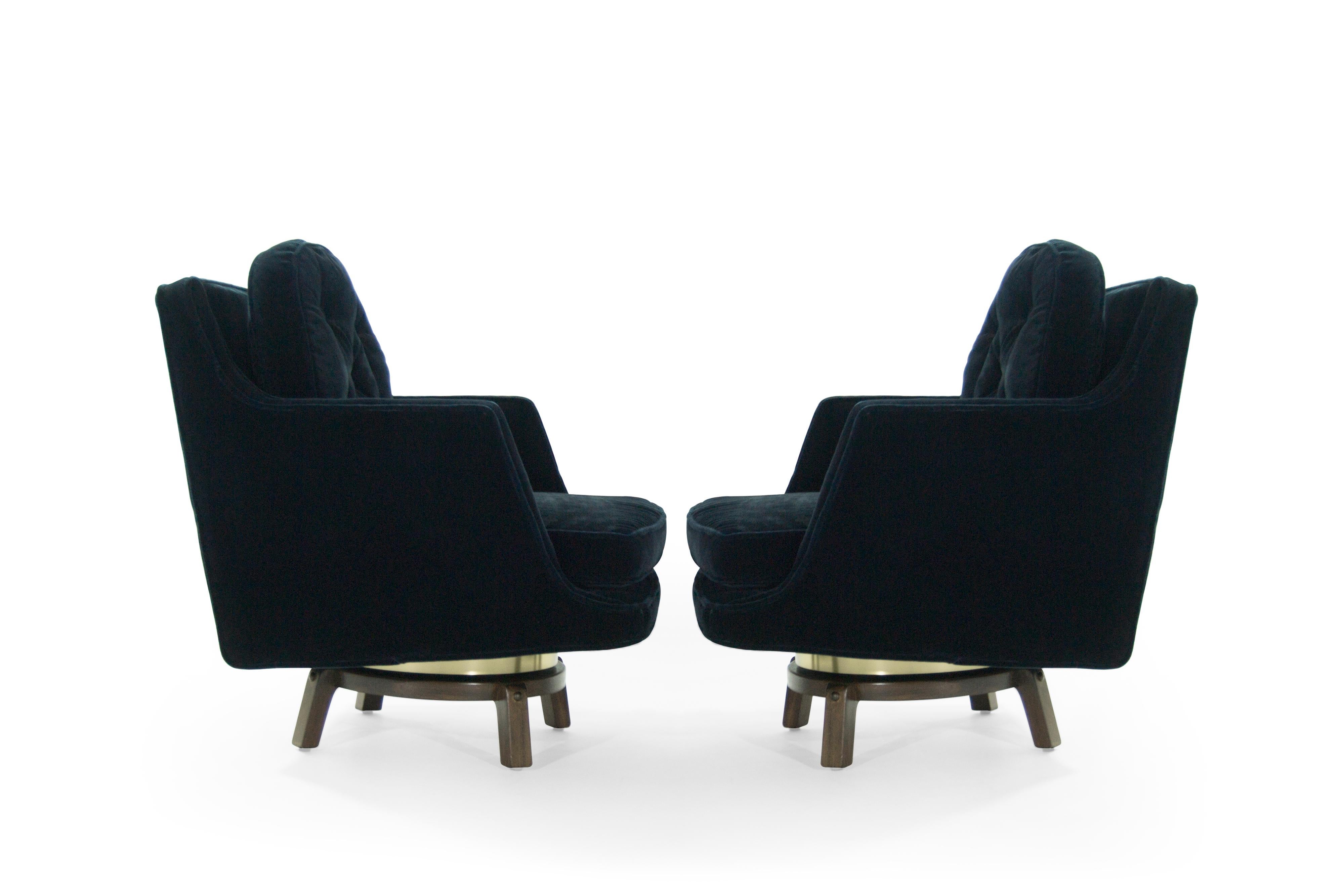 Pair of swivel lounge chairs designed by Edward Wormley for Dunbar, circa 1950s.

Re-upholstered in midnight blue mohair, fully restored walnut legs. Newly fitted polished brass ring.
