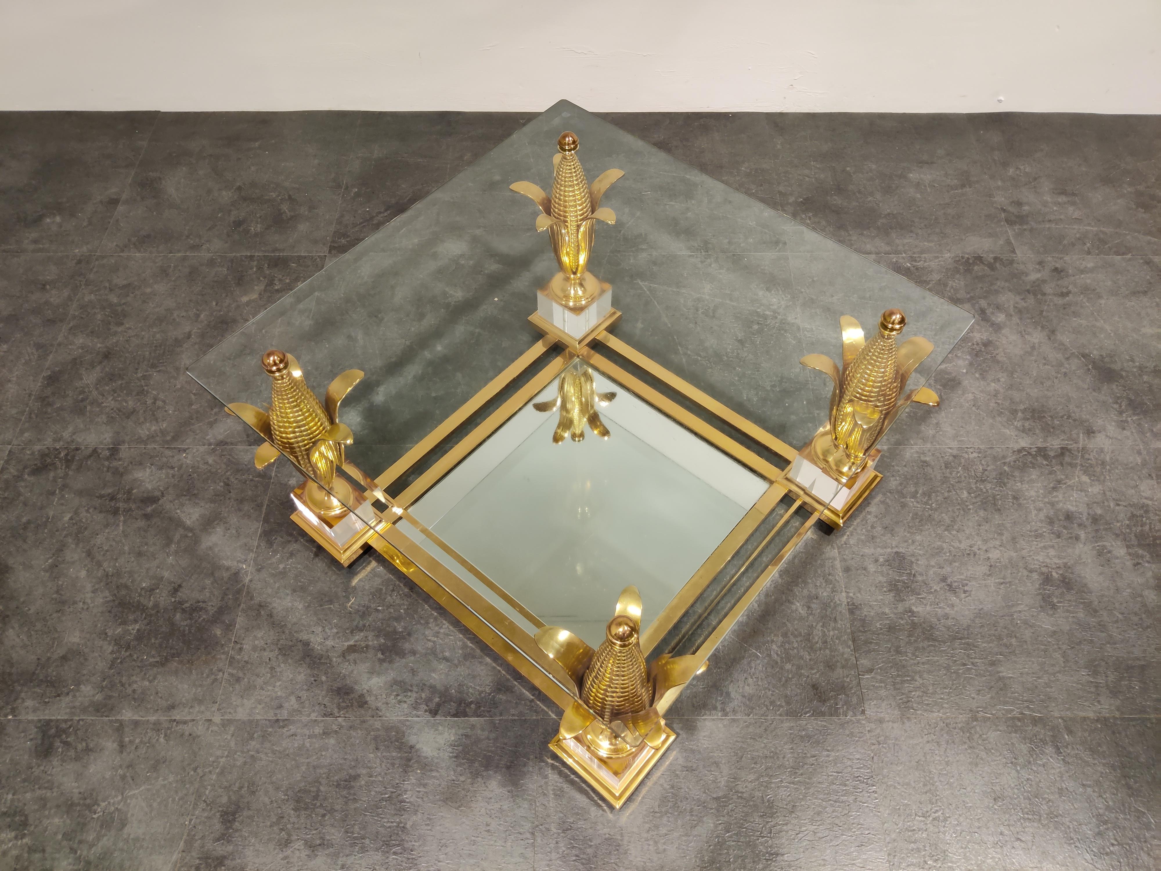 Stunning Hollywood Regency coffee- or side table with a clear beveled glass top and a mirrored glass at the bottom.

If features a brass and Lucite base with brass acorn shaped columns supporting the glass.

The acorns are very