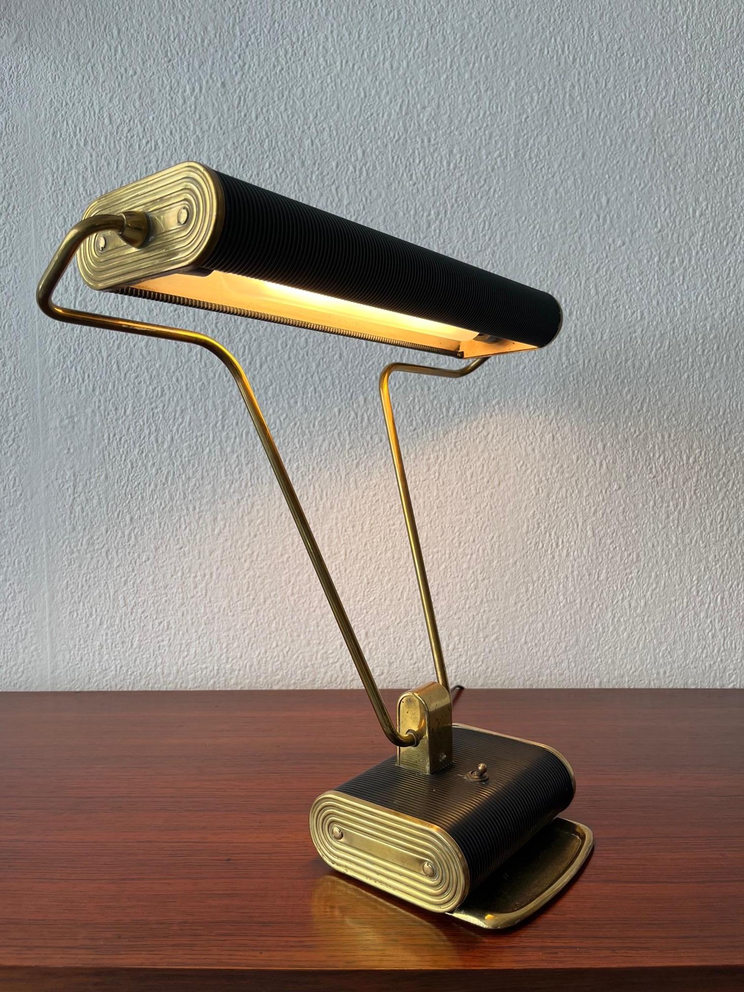Fantastique lampe de bureau n°71 en laiton et métal noir d'Eileen Gray produite par Jumo en France ca. 1930s
L'abat-jour et la tige sont réglables, ils peuvent être utilisés dans plusieurs positions.
L'ampoule (néon) est incluse et on peut trouver