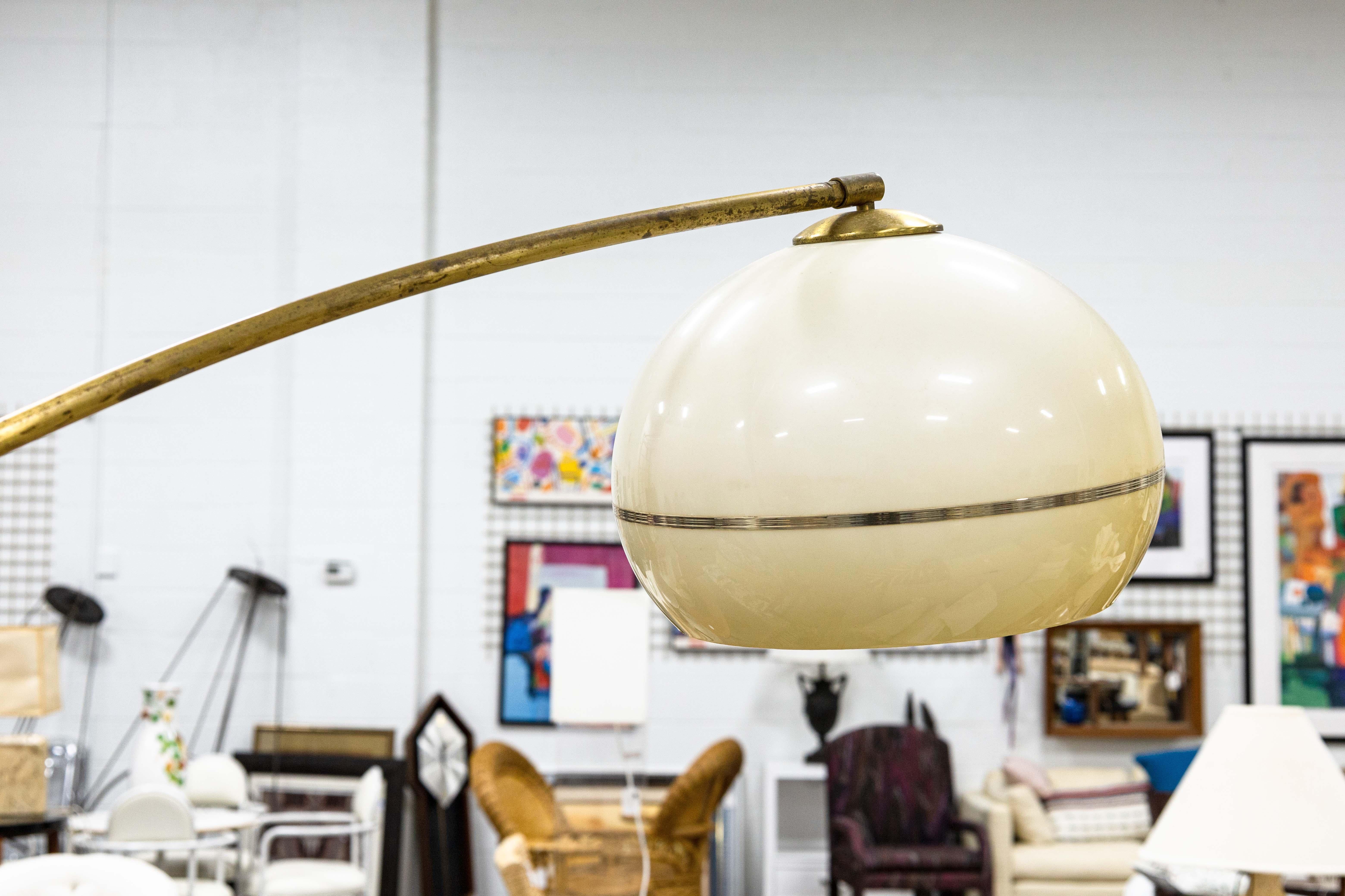 Una lampada da terra ad arco in ottone e marmo. Questa splendida lampada ad arco moderna di metà secolo presenta un insieme di materiali classici e moderni in ottone e marmo. Il paralume a forma di cupola è in acrilico bianco sporco con accenti