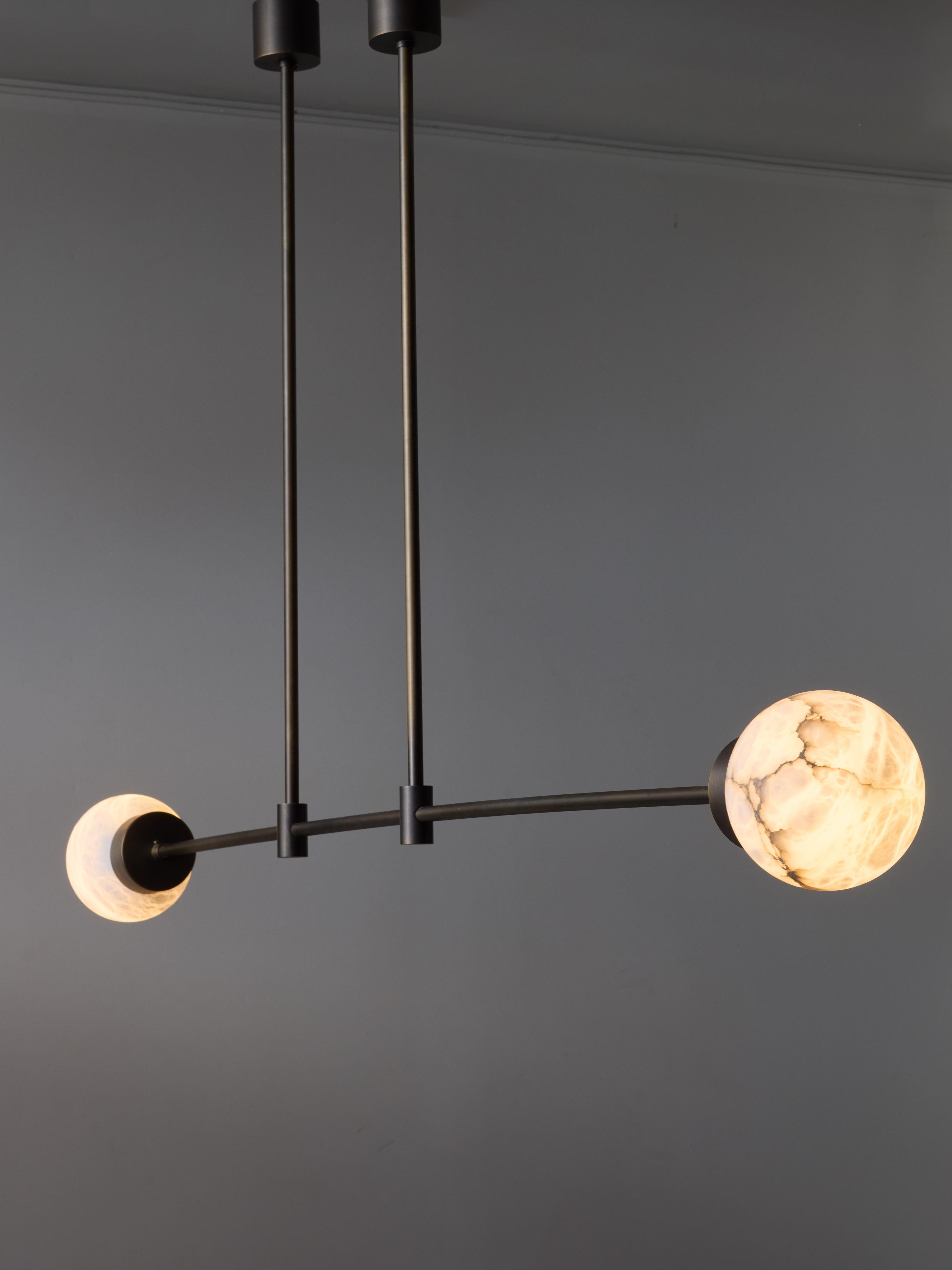 Lampadario in ottone con due sorgenti luminose racchiuse in globi di alabastro.

Il design raffinato e semplice di questo pezzo presenta una leggera torsione: un braccio di luce è leggermente più lungo dell'altro.