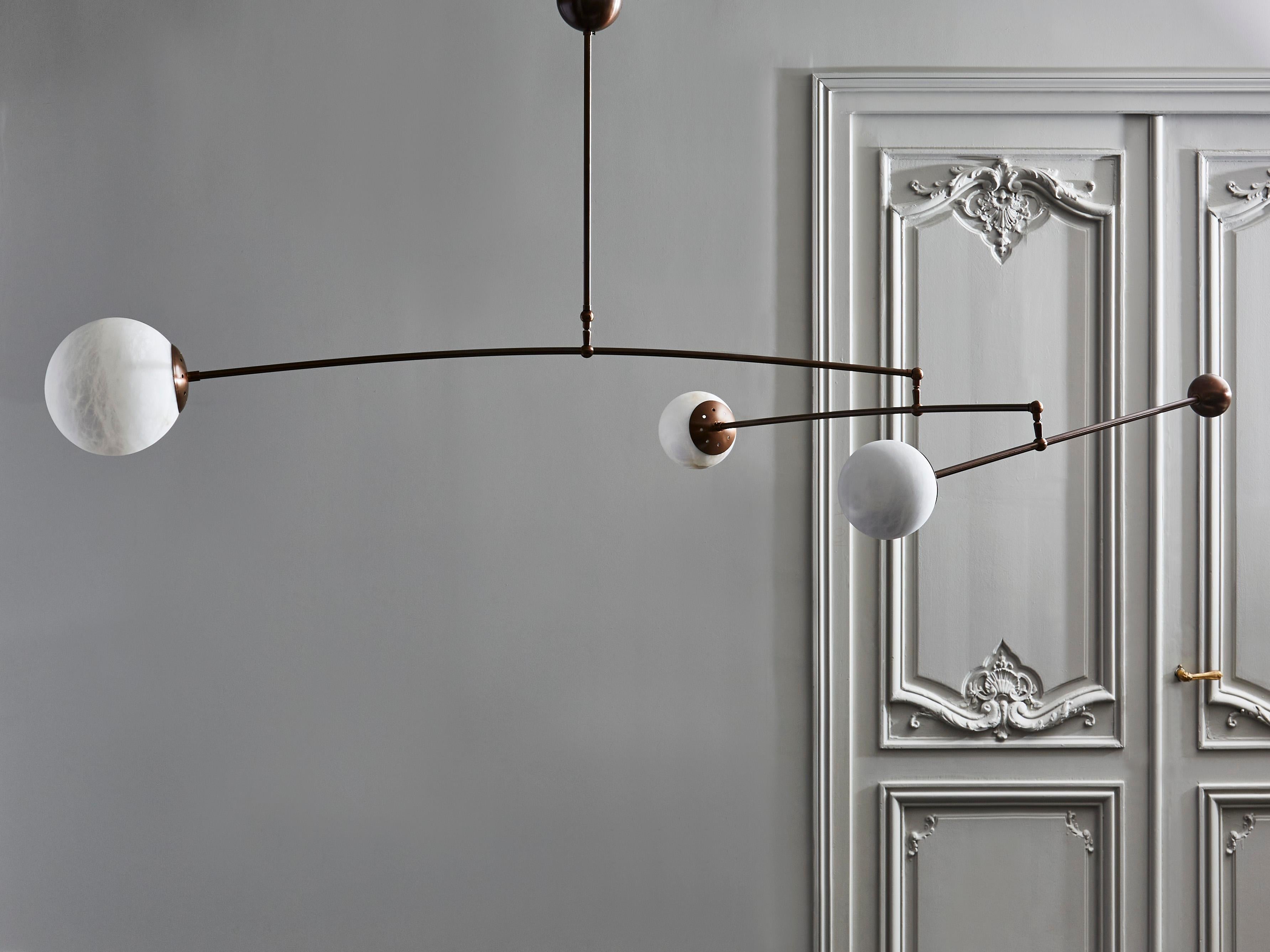 Lampadario mobile cinetico composto da tre bracci di luce in ottone patinato, ognuno dei quali sostiene globi di alabastro di dimensioni diverse e un contrappeso per garantire l'equilibrio del pezzo.

Design originale di Glustin Luminaires.