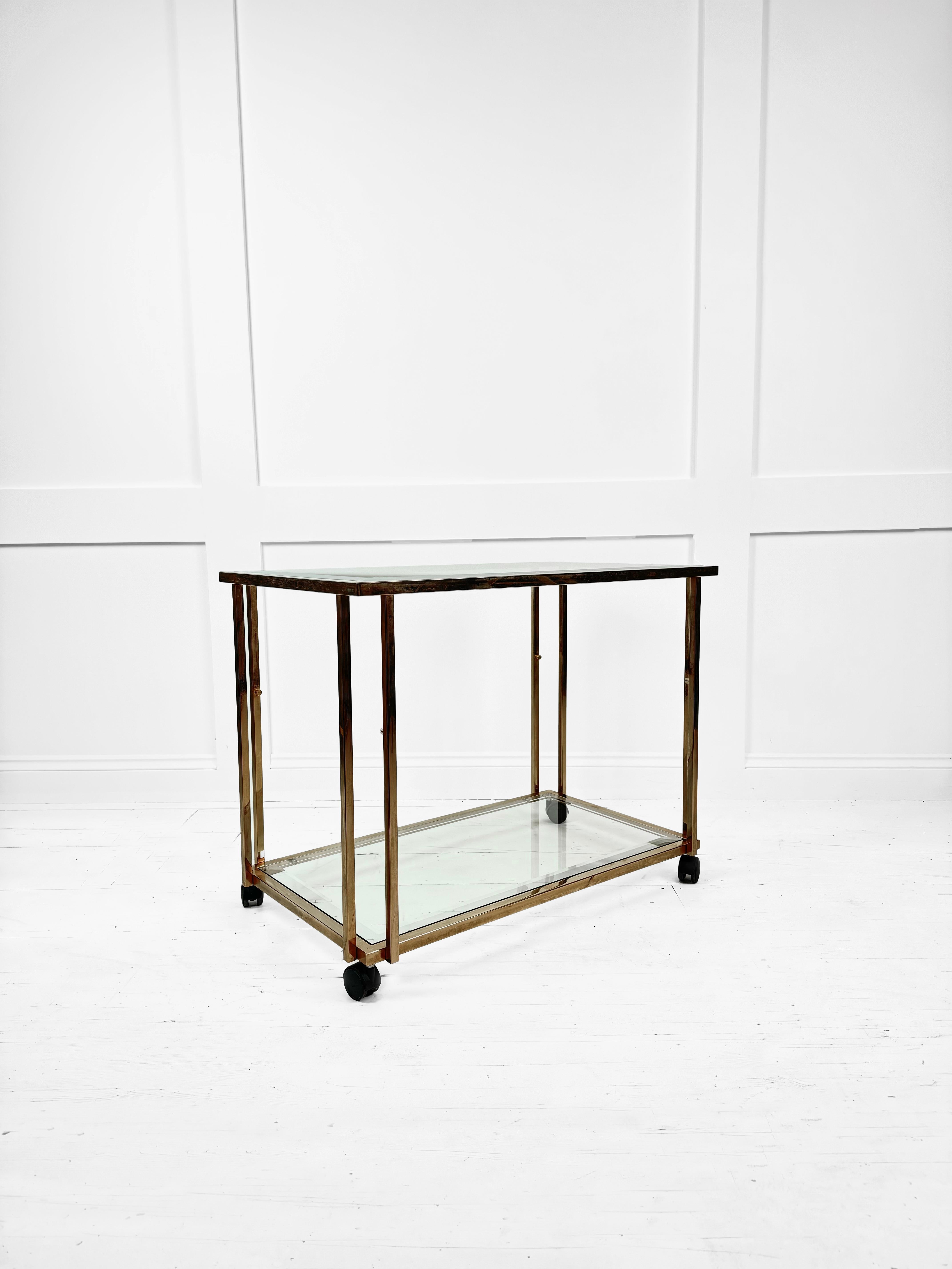A distinctive touch of vintage elegance with this stunning Brass and Bevel Glass Drinks Trolley from Belgium, dating back to the 1980's. The trolley features a sleek brass frame with decorative detailing and a bevel glass top and bottom shelf that