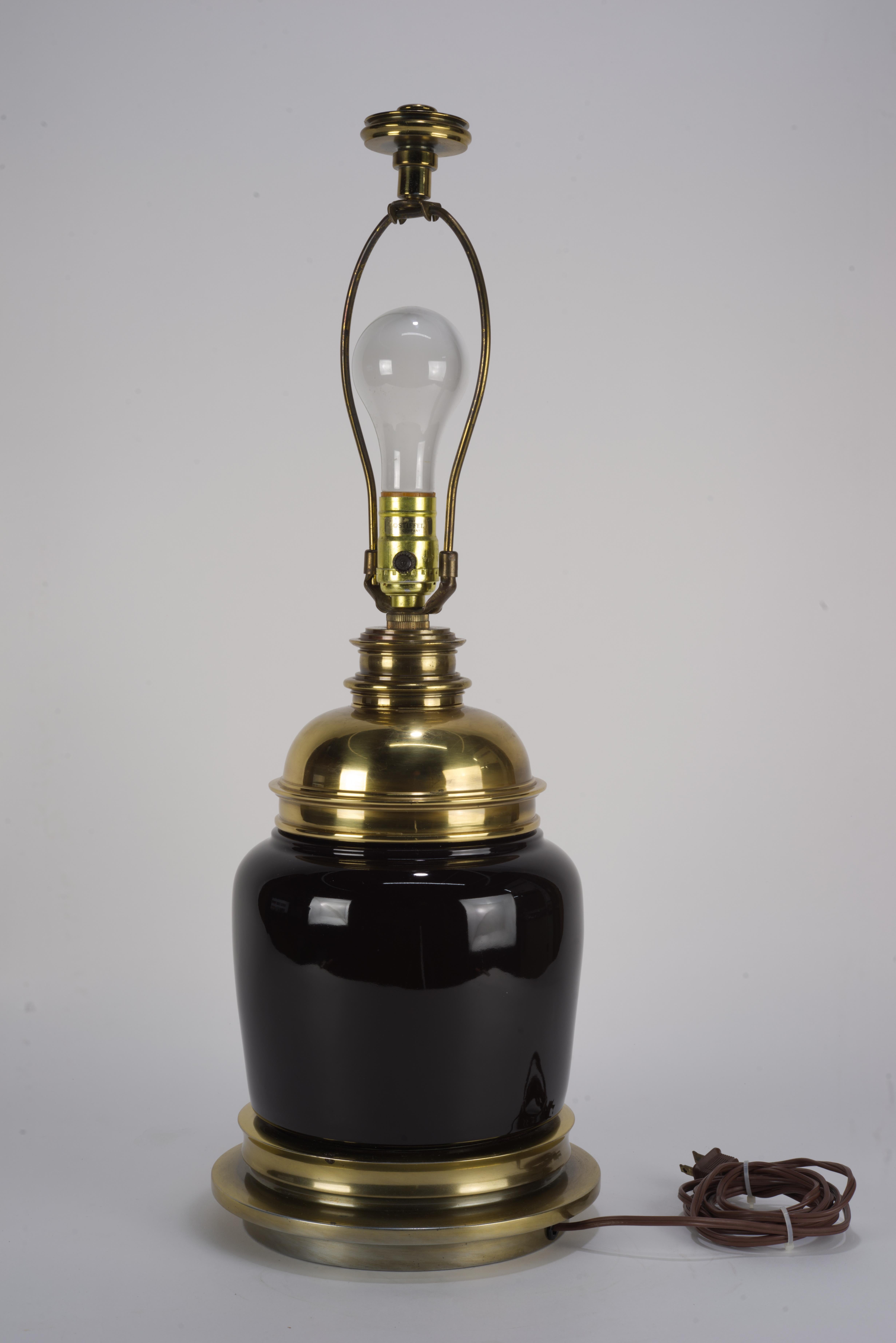  Large table lamp was made by Stiffel in traditional style with heavy brass accents and the base and statement black ceramic body. It has the original harp and finial.

The lamp measures24.5