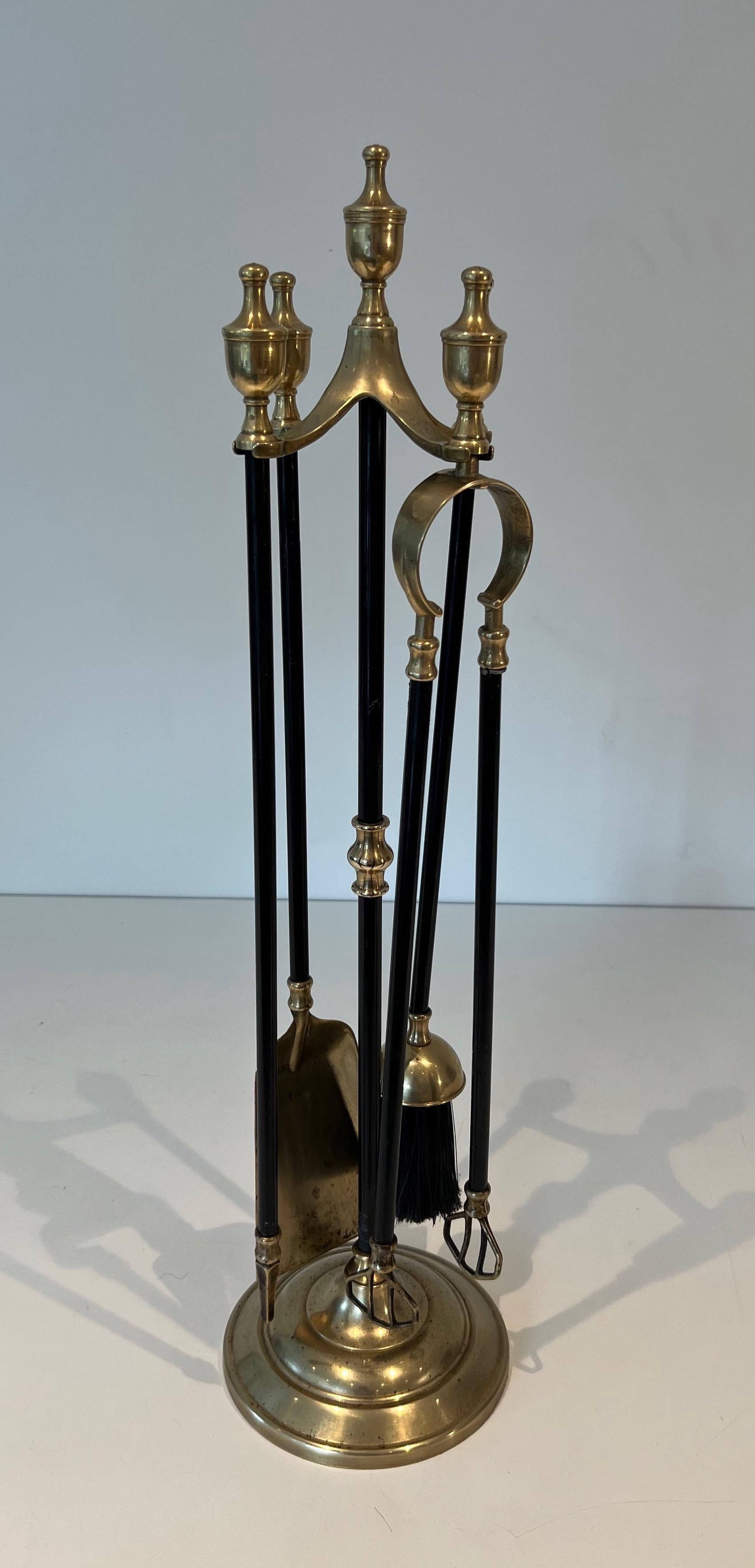 This neoclassical style fireplace tools on stand is made of brass and black lacquered metal. This is a French work. Circa 1940