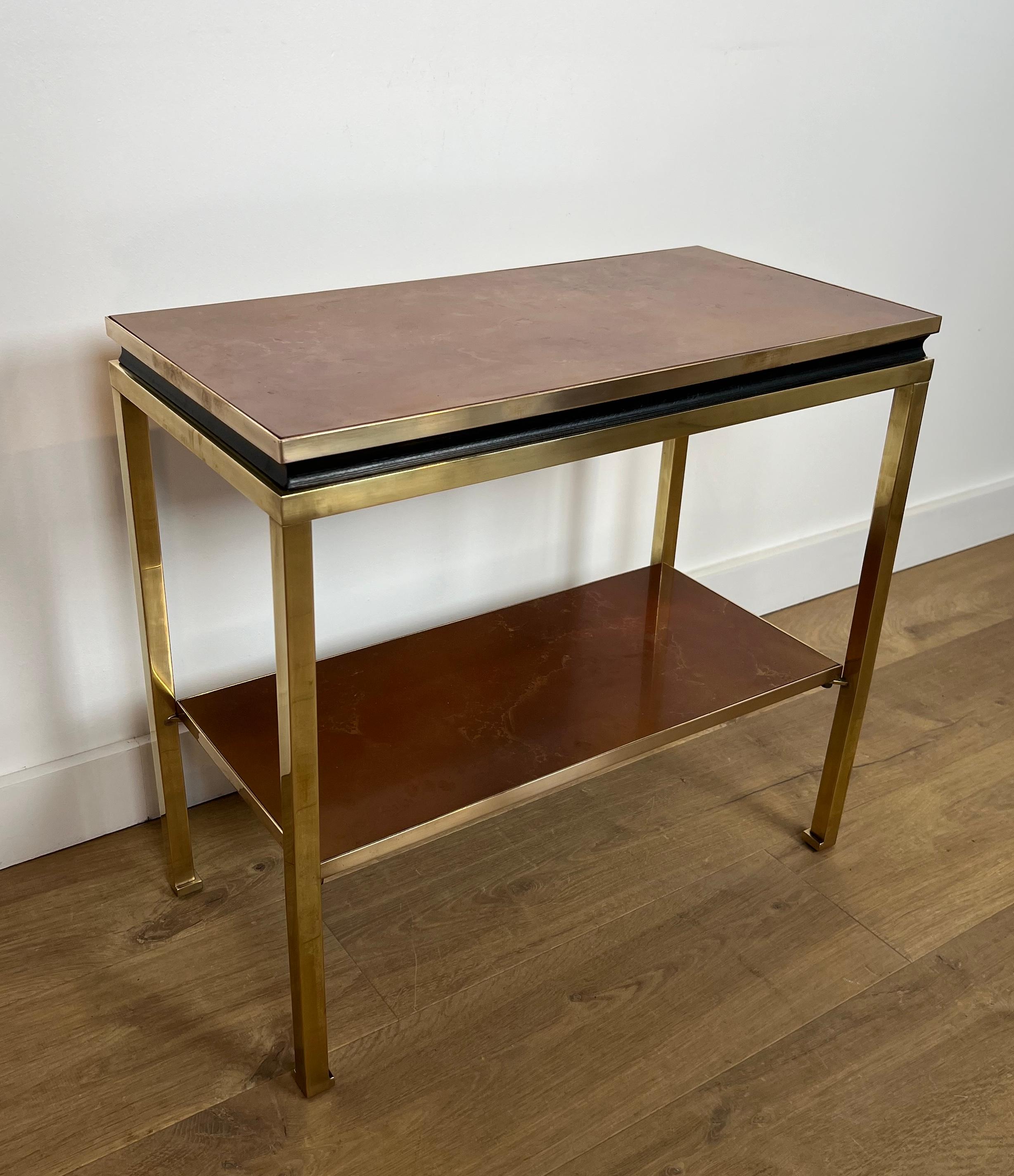 Questo grazioso ed elegante tavolino o consolle è realizzato in ottone e metallo laccato nero con ripiani in celluloide color ambra. Si tratta di un'opera francese del famoso designer Guy Lefèvre per la Maison Jansen. Circa 1970