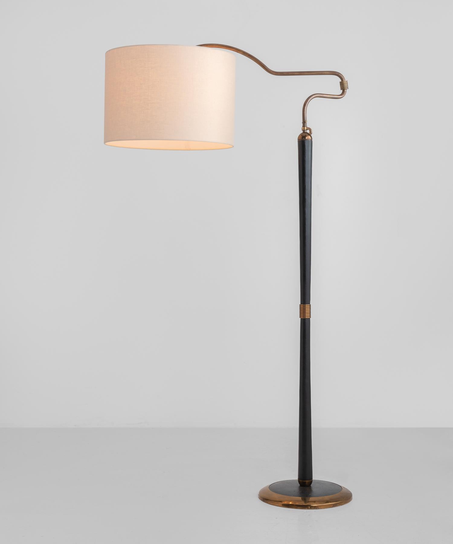 Brass and black leather floor lamp, England, circa 1950.

Articulating brass arm, adjustable in height, with new linen shade.

Measures: 19