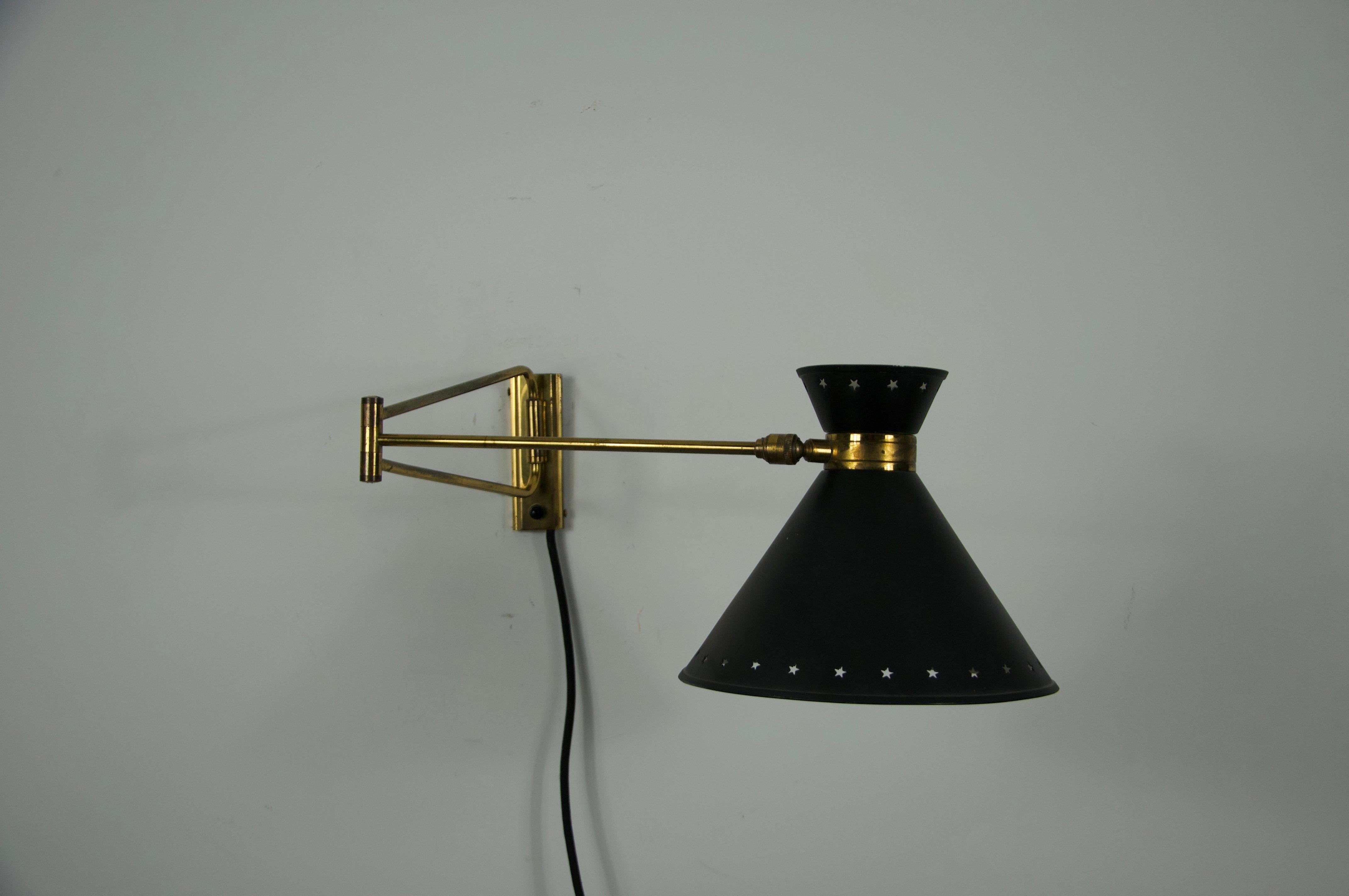 Este elegante aplique de latón y negro, diseñado por René Mathieu para Maison Lunel en la década de 1960, encarna la refinada estética del diseño de iluminación francés de mediados de siglo. La pieza presenta una llamativa pantalla cónica en negro