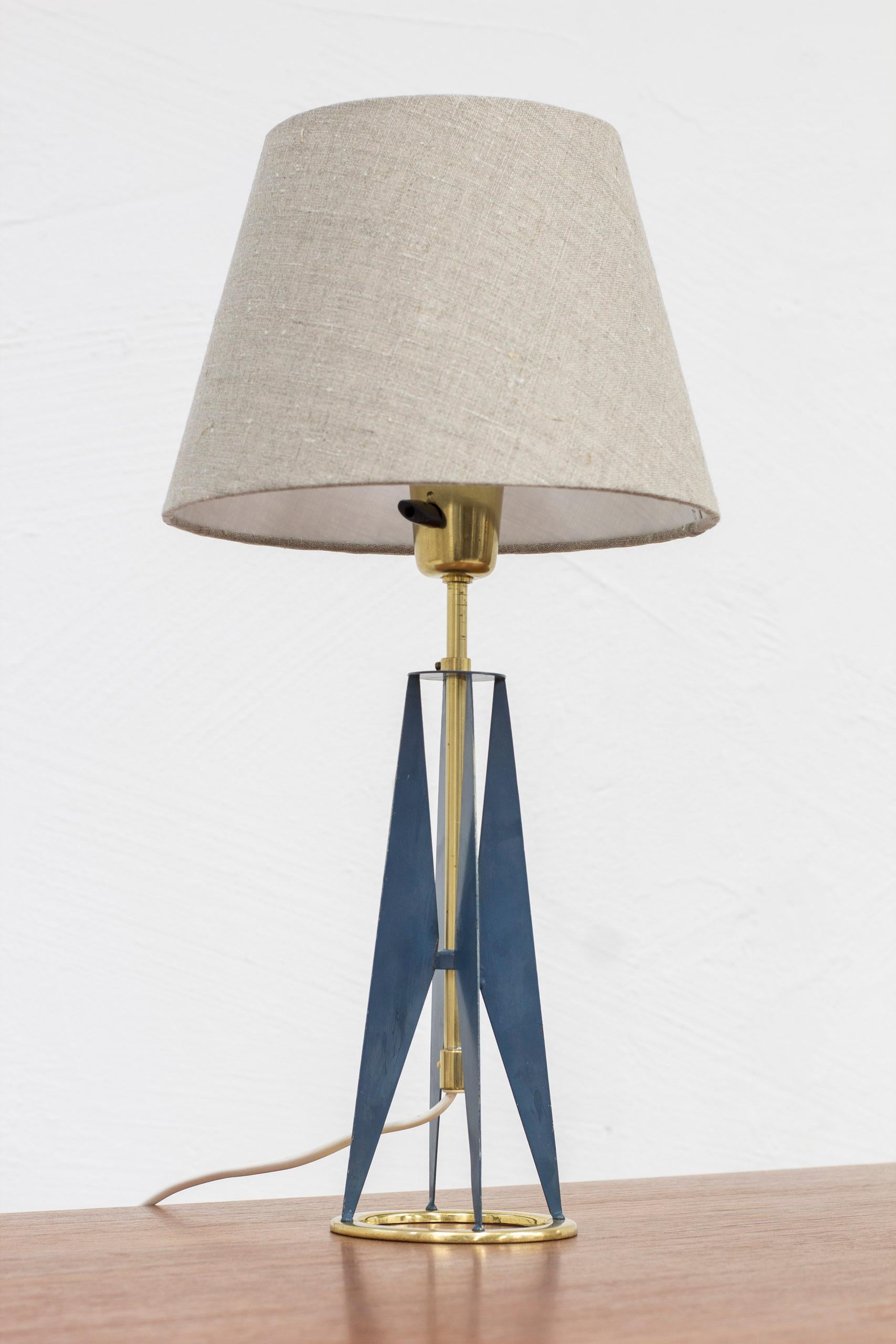 Table lamp produced in Sweden by Falkenbergs Belysning. Made sometime during the 1950s. Made from polished brass and metal with original blue paint. Original bakelite turn light switch in working order. New lamp shade in grey linen fabric. Good