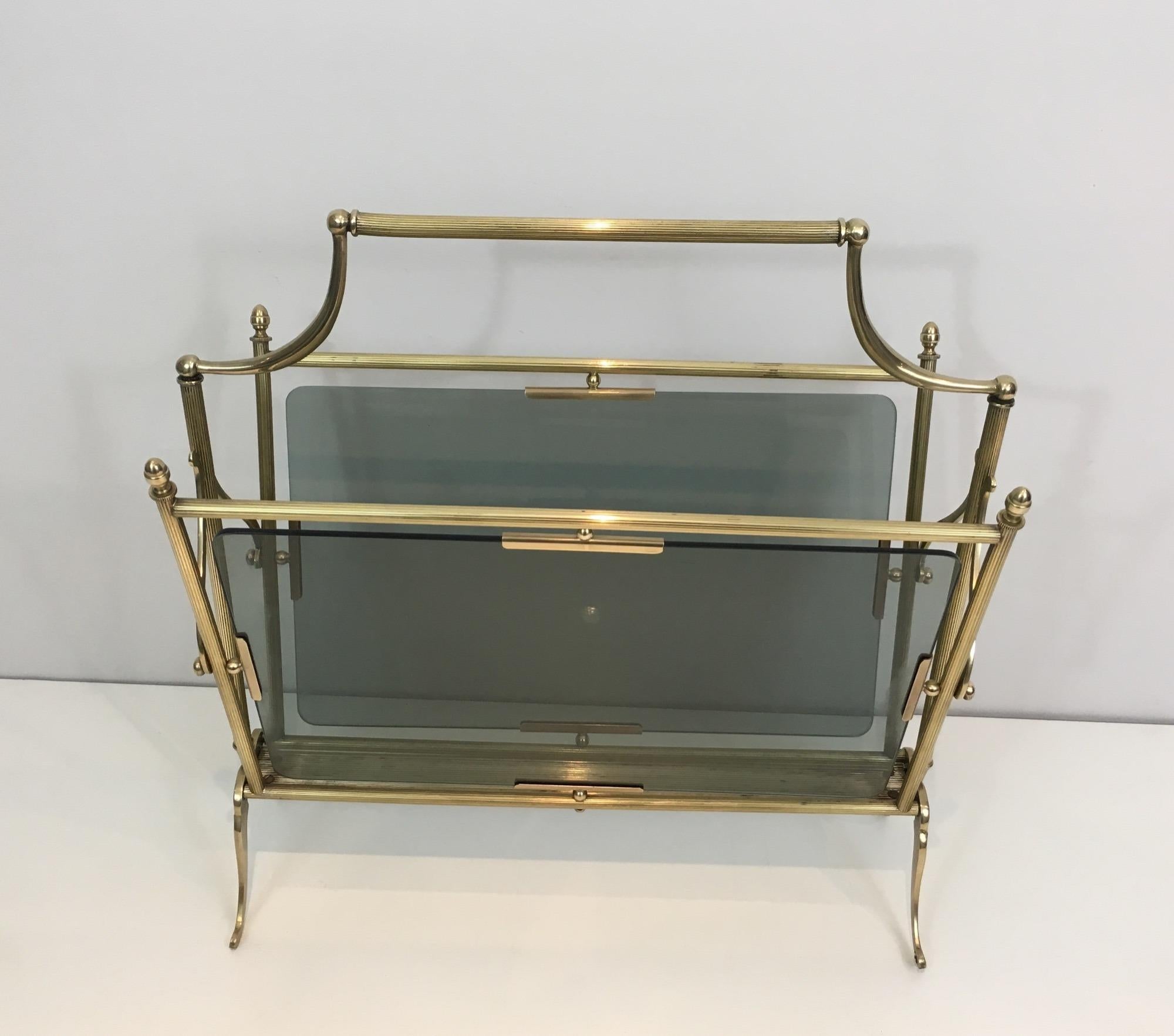 This neoclassical style magazine rack is made of brass with blueish glass . This is a French work by Maison Jansen. Circa 1940. A pair is available