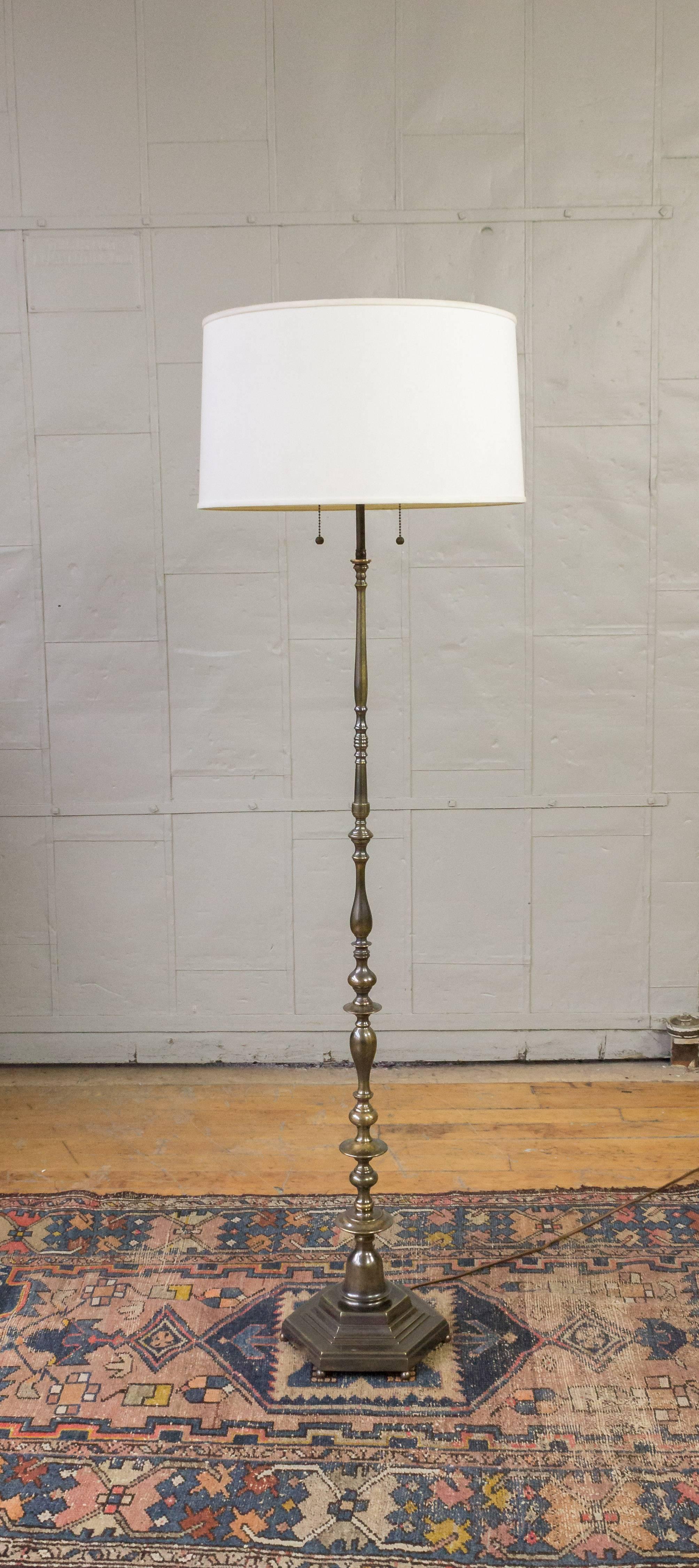This beautiful French 1940s floor lamp boasts a cast hexagonal base that sits on ball feet, adding stability and elegance to its design. The stem of this lamp is made up of turned and cast bronze components that taper elegantly to create a unique