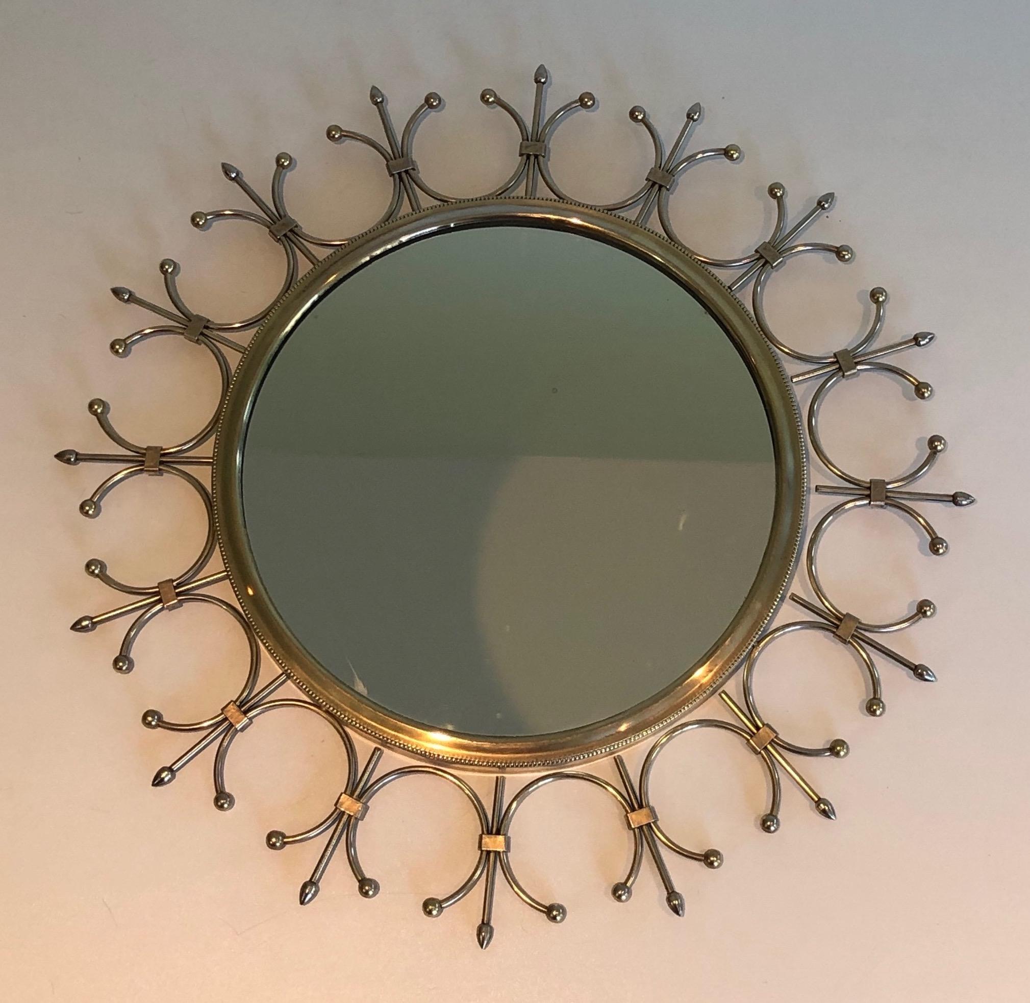 This delicate and decorative sunburst mirror is made of brass and brushed steel. This is a French work. Circa 1970.