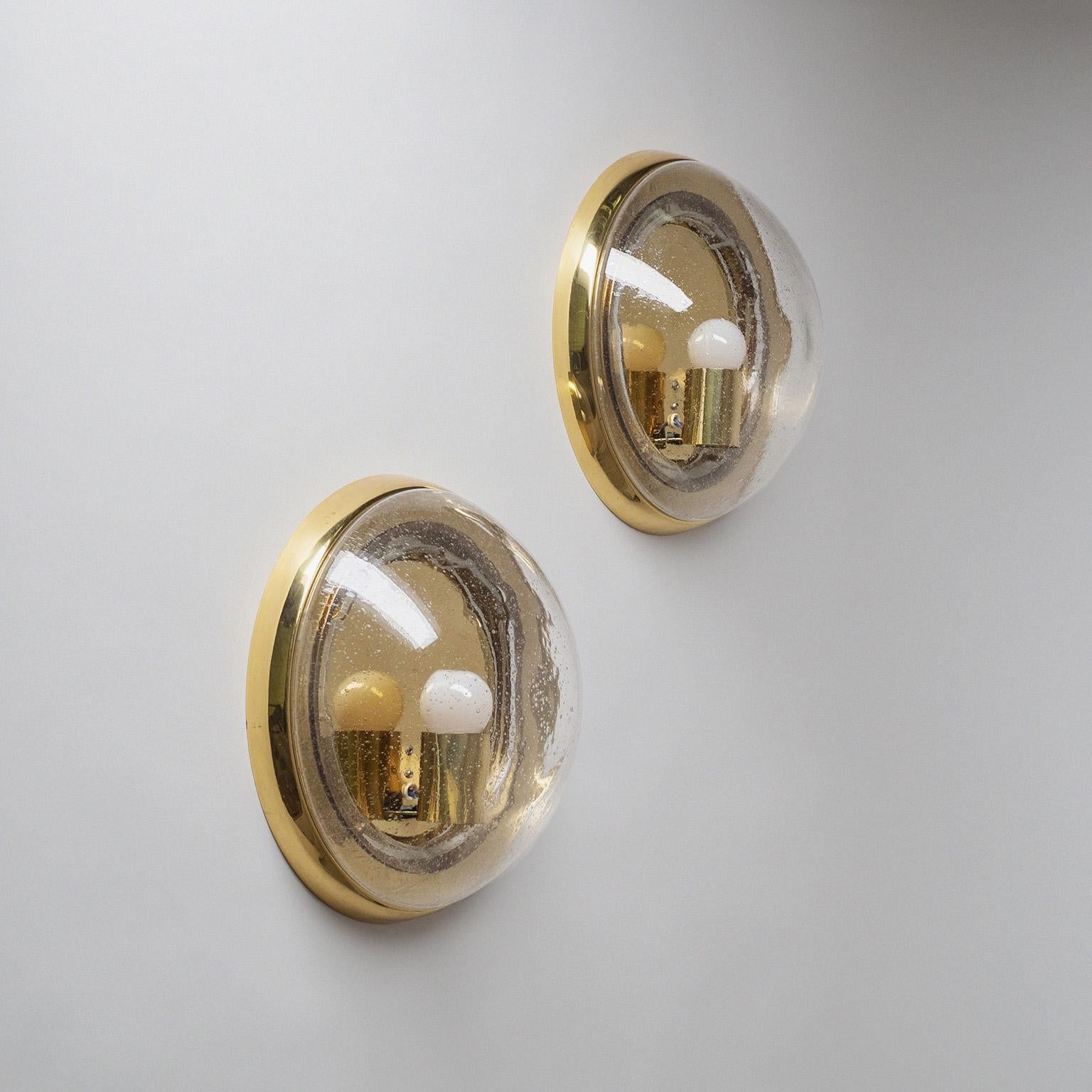 Pair of large brass ‚bullseye‘ wall lights by Hillebrand, Germany from the 1970s. The blown clear glass domes are filled with small bubbles and have a slightly irregular surface contrasting nicely with the smooth brass hardware. Very good original