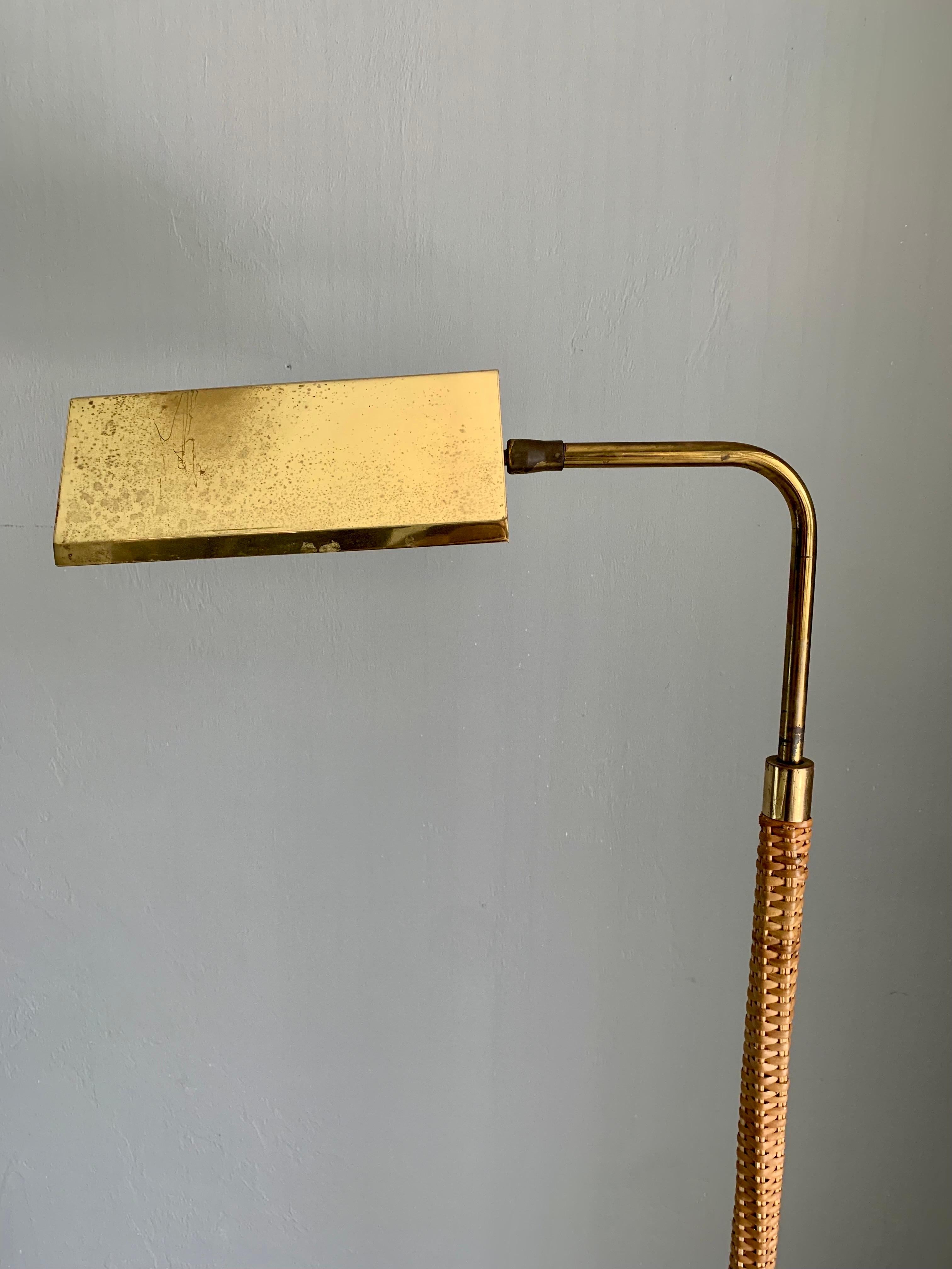 A floor lamp, made by an unknown designer. Brass rod construction with the bottom portion expertly wrapped in cane. 

Adjustable height and shade. All brass. The switch allows you to sim the lamp to desired brightness. 

Beautiful patina through