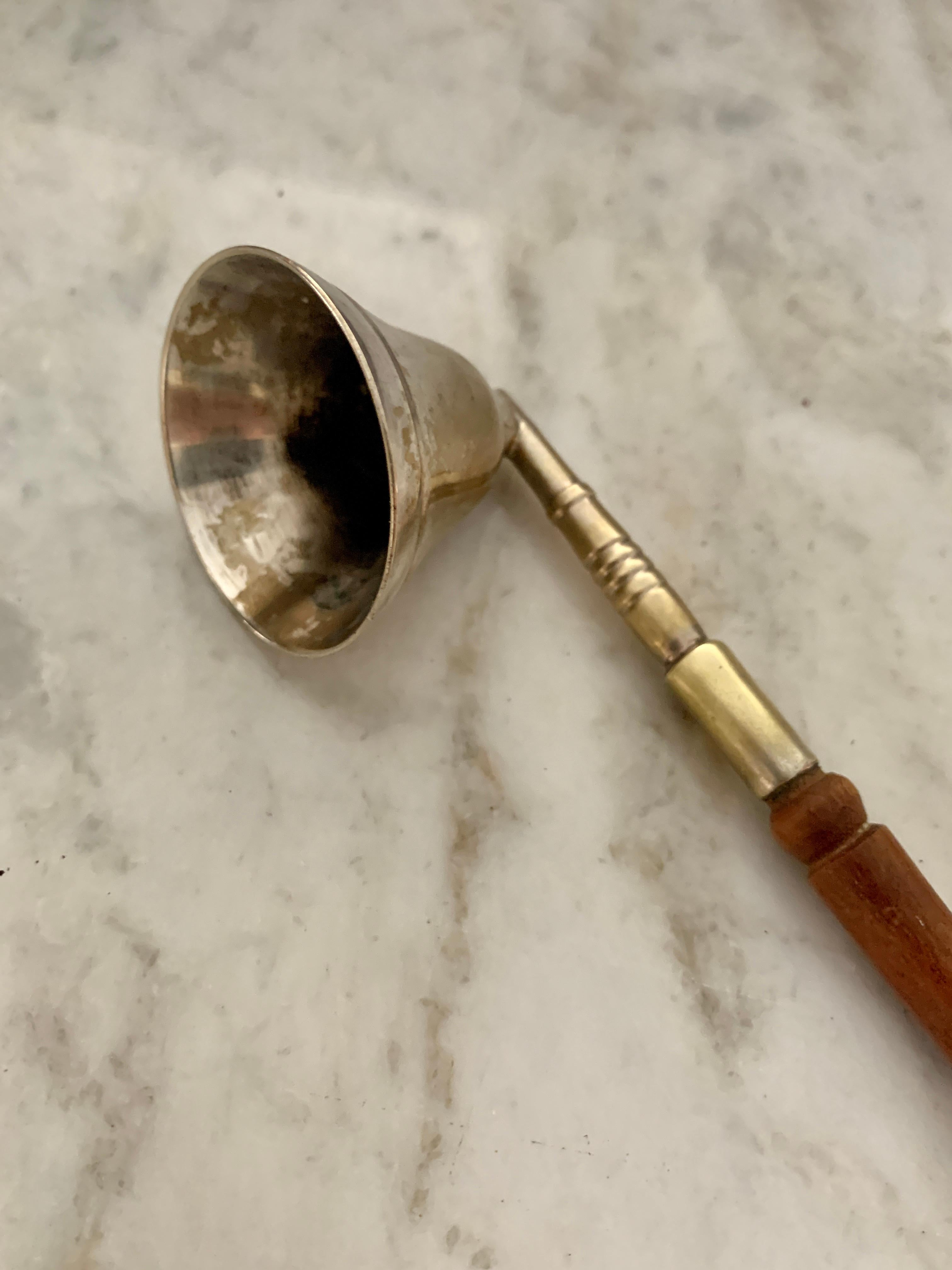 Candle snuffer of carved wood handle and brass housing to put out a flame. The handle is long and carved. The tip has a piece missing, however, rather than cut it off, we left it as it adds character and is not terribly noticeable. A very nice