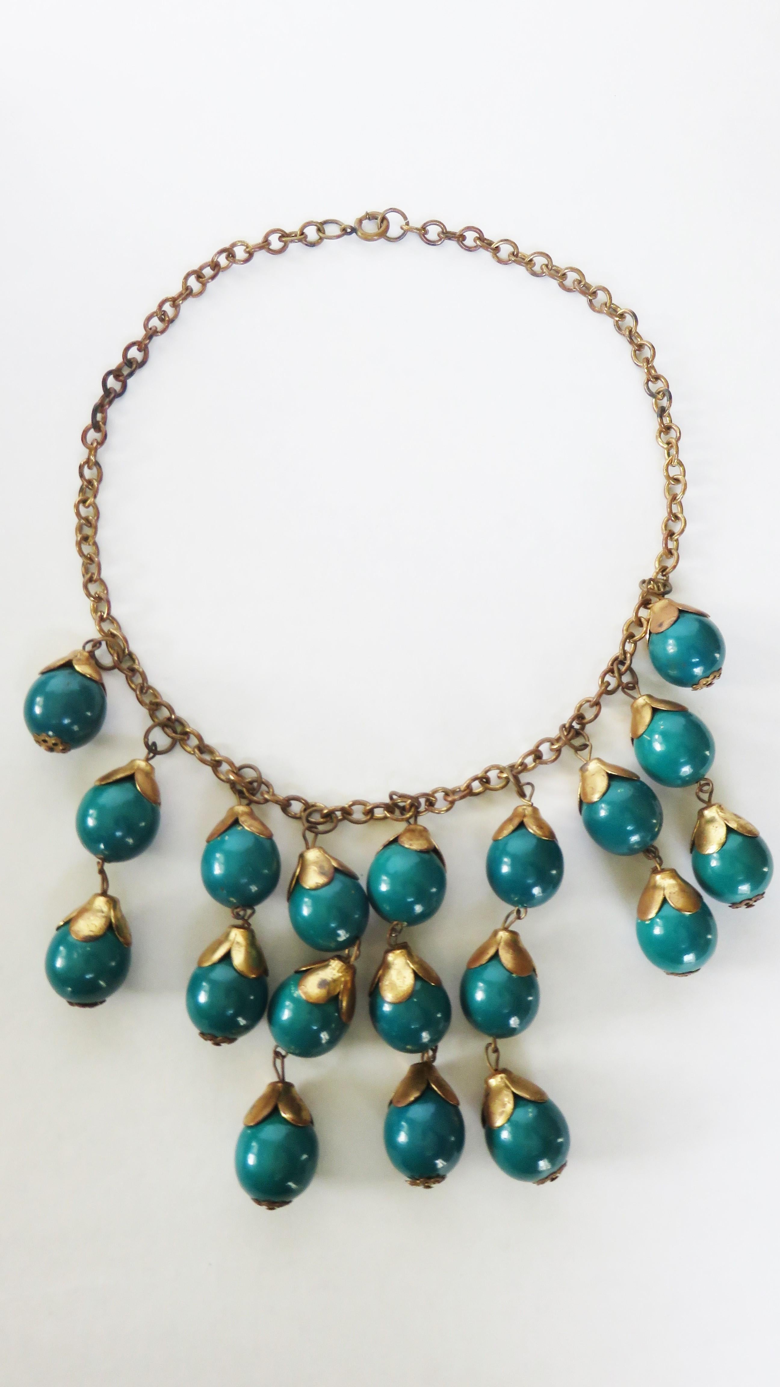 A gorgeous Brass chain and emerald color celluloid ball drop necklace. There are nine drops at the center front with 3 rows of 3 dangling balls flanked by 2 balls on either side followed by one ball.  It closes with a spring ring clasp.

Length 