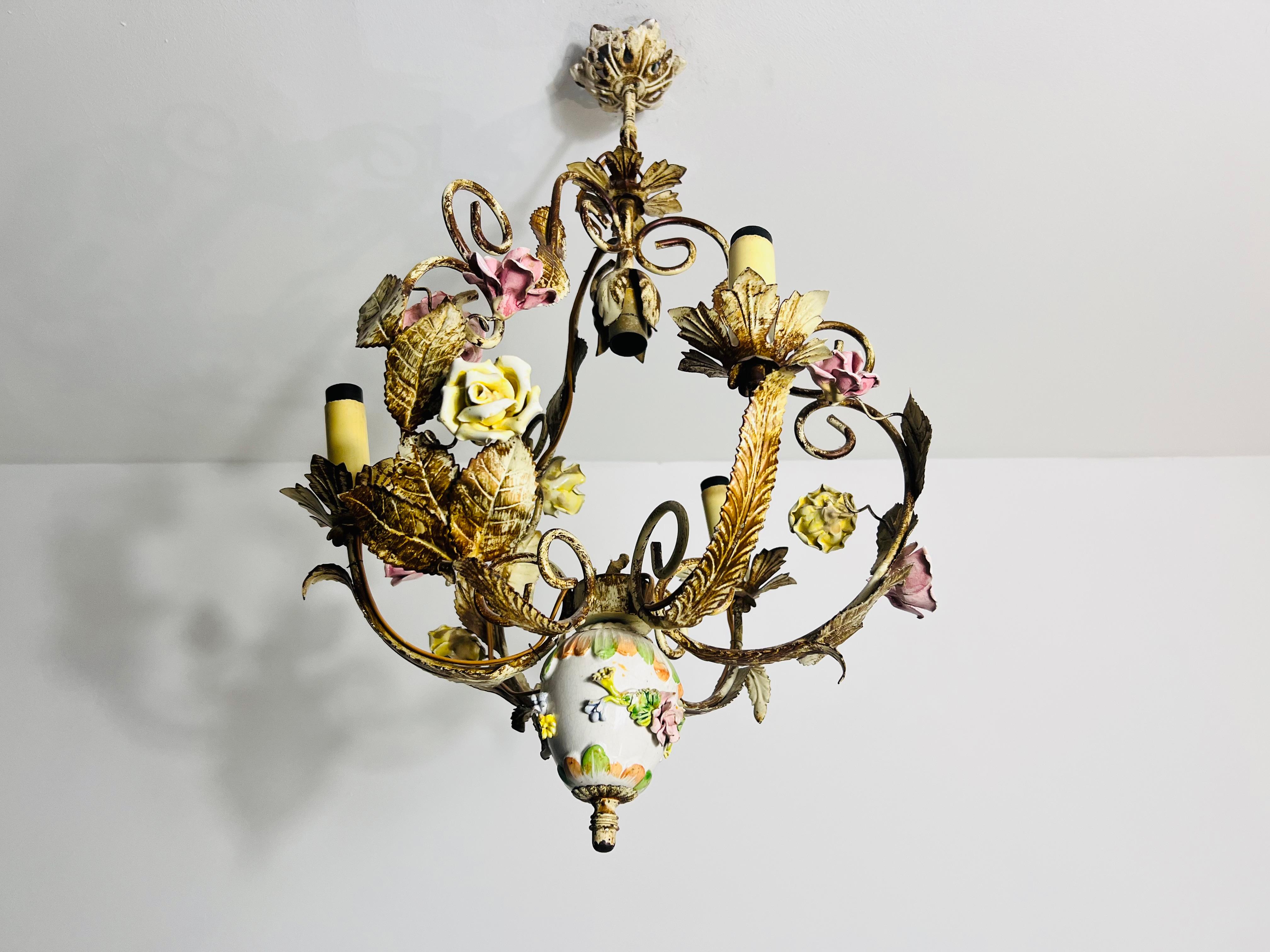 Questo splendido lampadario proveniente dalla Germania degli anni '70 sfoggia un bellissimo disegno floreale che incarna l'eleganza dell'epoca Regency di Hollywood. La lampada presenta foglie in ottone lavorate in modo intricato e fiori colorati in
