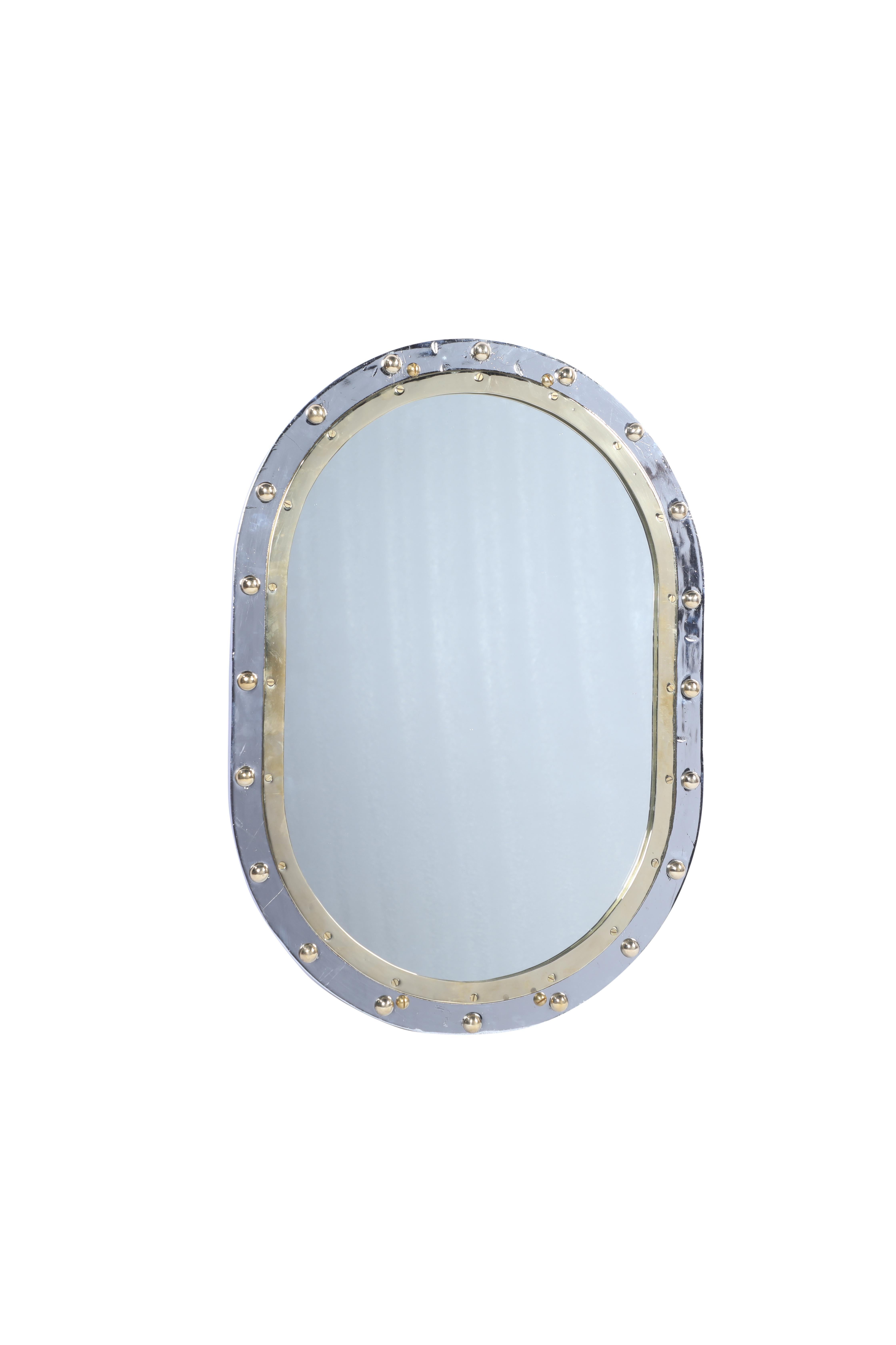 From a decommissioned ship, an oval fixed porthole window in a combination of chrome and brass converted by us into a mirror. Classic styling. Rivets were added as these come out when taken off ships. Two brass supports on the back for hanging and