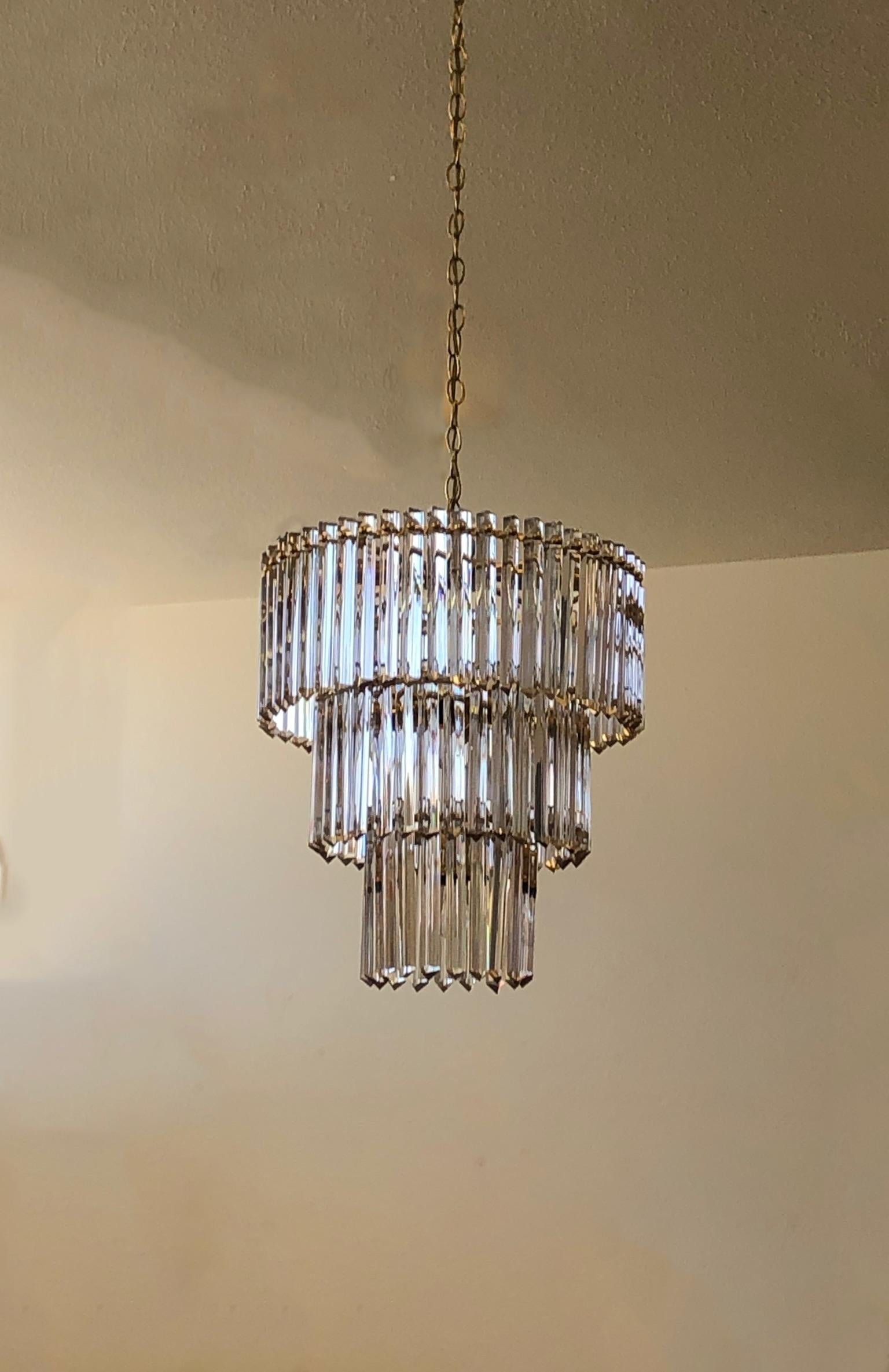 Three tiered clear crystals and polish brass chandelier from the 1970’s.
Shows minor wear consistent with age. 
Takes eight candelabra size bulbs and one regular Edison lightbulb. 
Ceiling cap included, we can make the chain any length you want.