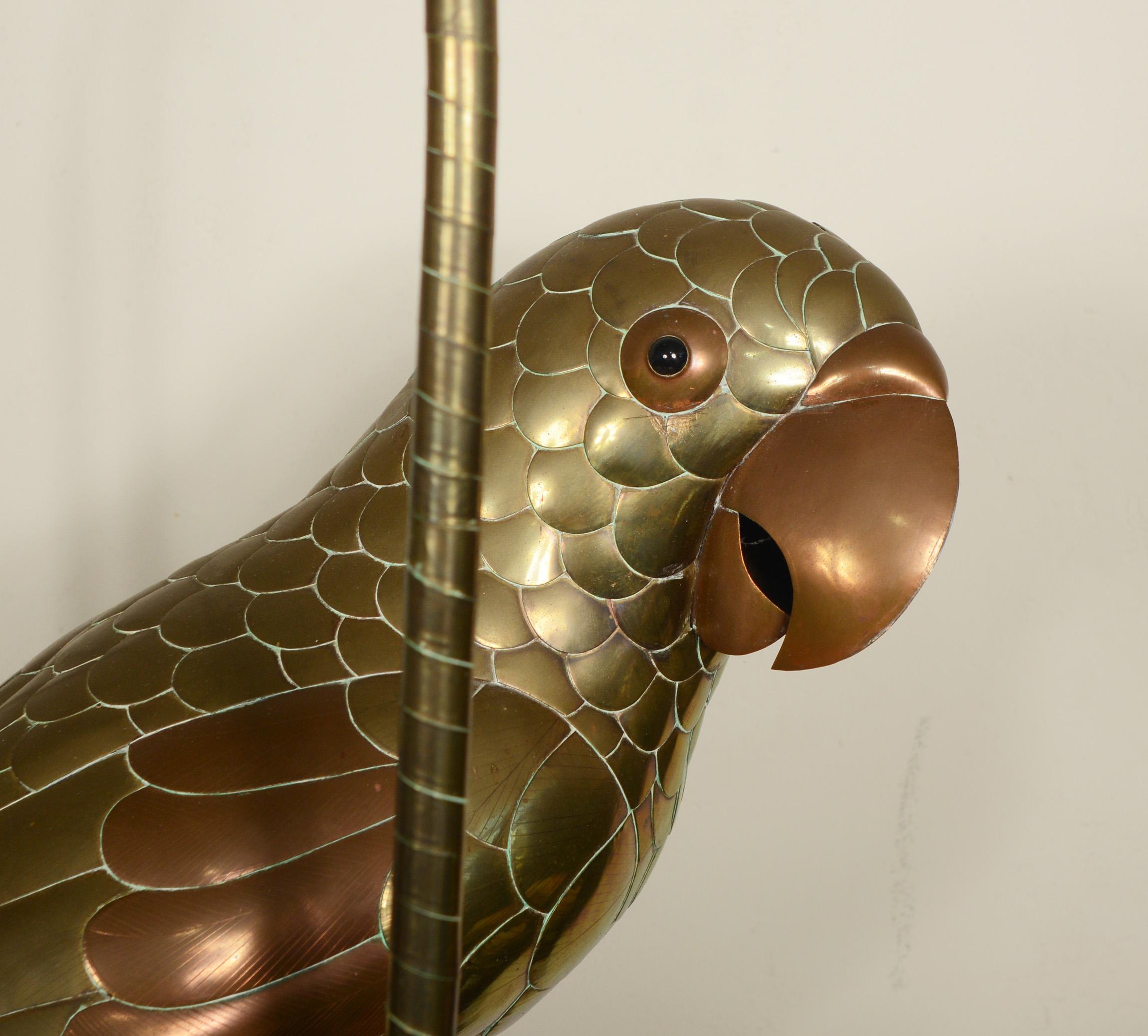 Brass and copper parrot on a perch by Sergio Bustamante. There are a few dings and small dents. One seam between two tail feathers has separated.
