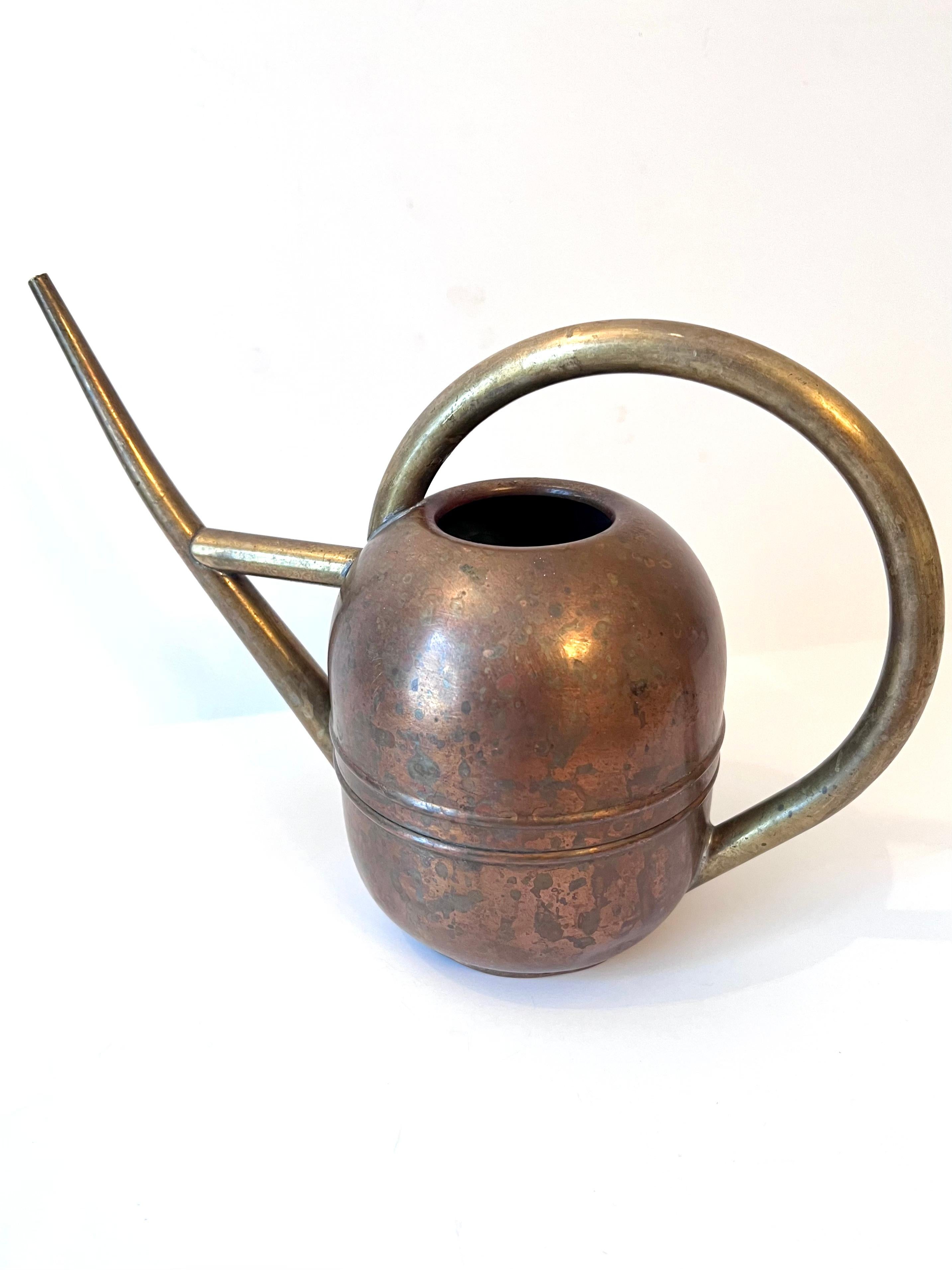 A period Art Deco watering can with beautifully patinated brass and copper. A fully functional piece to water the plants or a compliment to many settings as a decorative piece. The patination is lovely.