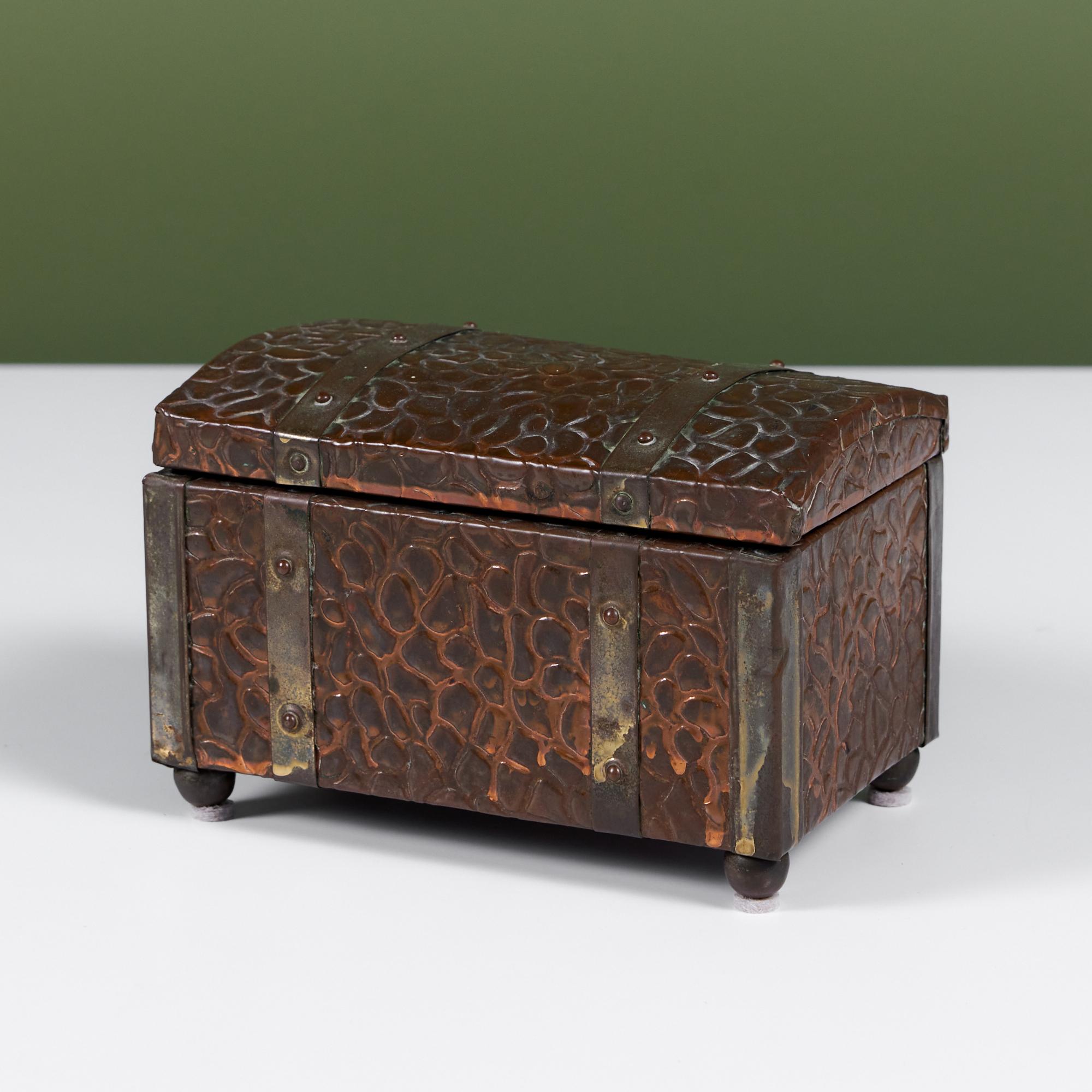 Boîte en cuivre texturé avec détails en laiton. L'extérieur de la boîte présente une texture semblable à celle des galets, parfaitement patinée, avec des charnières en laiton, des pieds en forme de boule et des détails. La boîte à charnières est