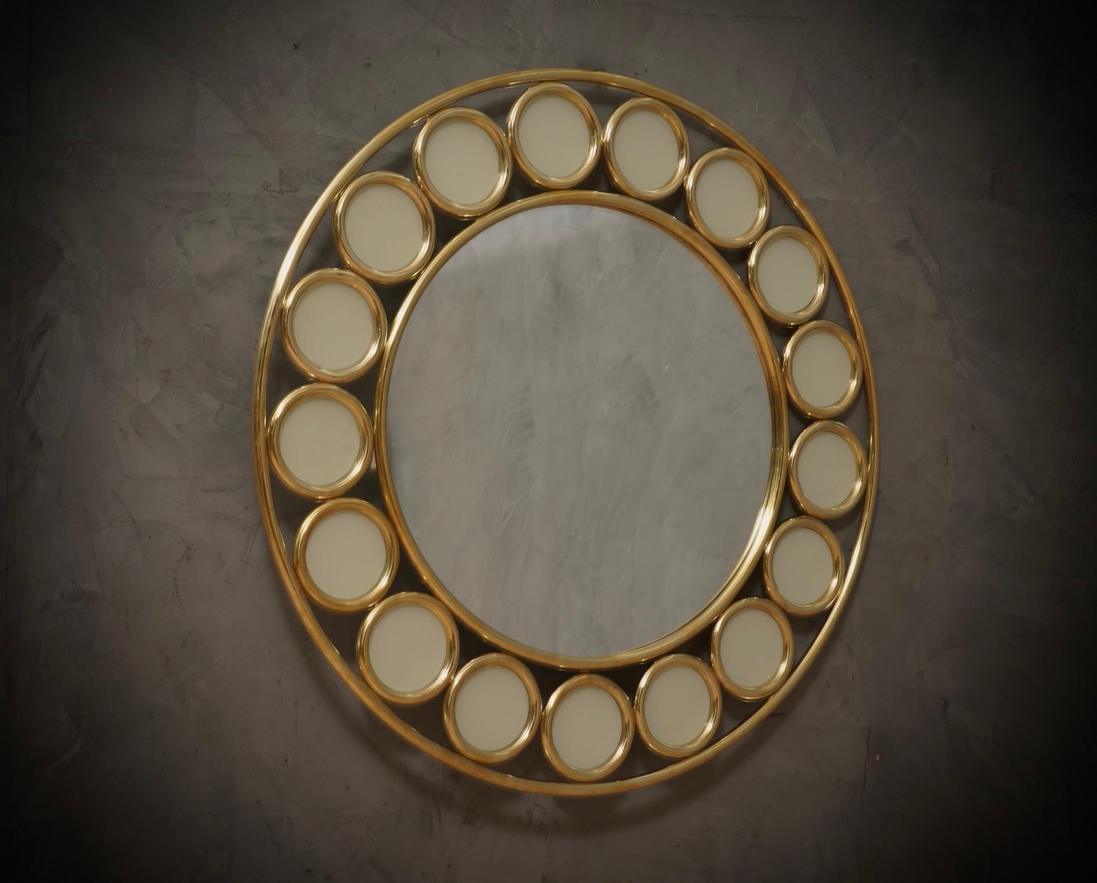 A strong brass frame with a particular round design reaches the eye of the beholder, leaving him entranced; wall mirror in cream-colored Murano artistic glass. Original and characterful, with a beautiful shape and excellent dimensions, the wall
