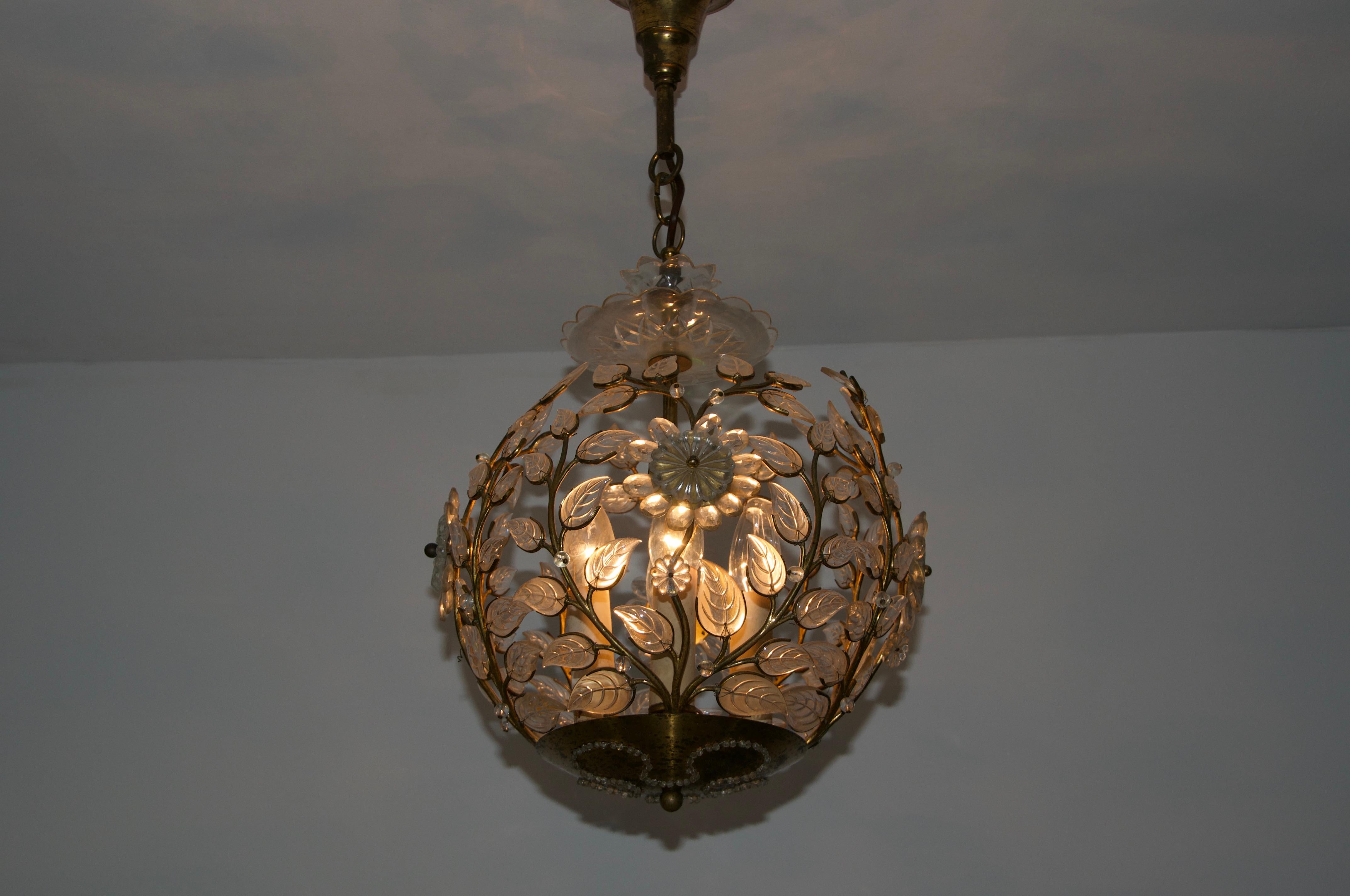 This exquisite chandelier from the 1960s, designed by Ernst Palme, is a true statement piece that embodies elegance and craftsmanship. The spherical brass frame is adorned with intricate floral and leaf motifs, each delicately crafted from clear