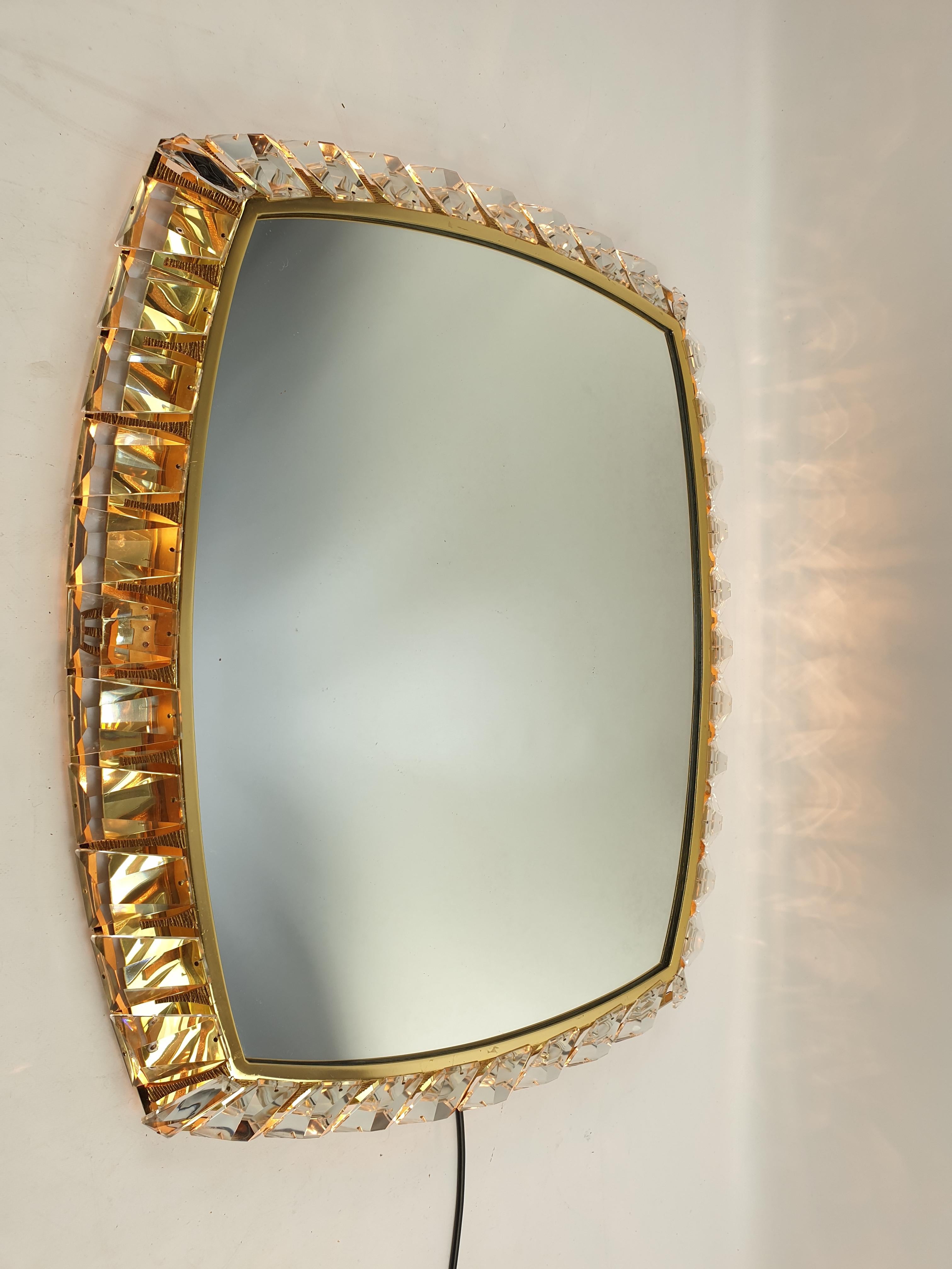 This is a real luxury wall mirror with many big size shiny crystals around the brass mirror frame. The mirror can be illuminated from inside and creates a gorgeous brilliant light. In reality the lamp has a more golden shine than is seen in the