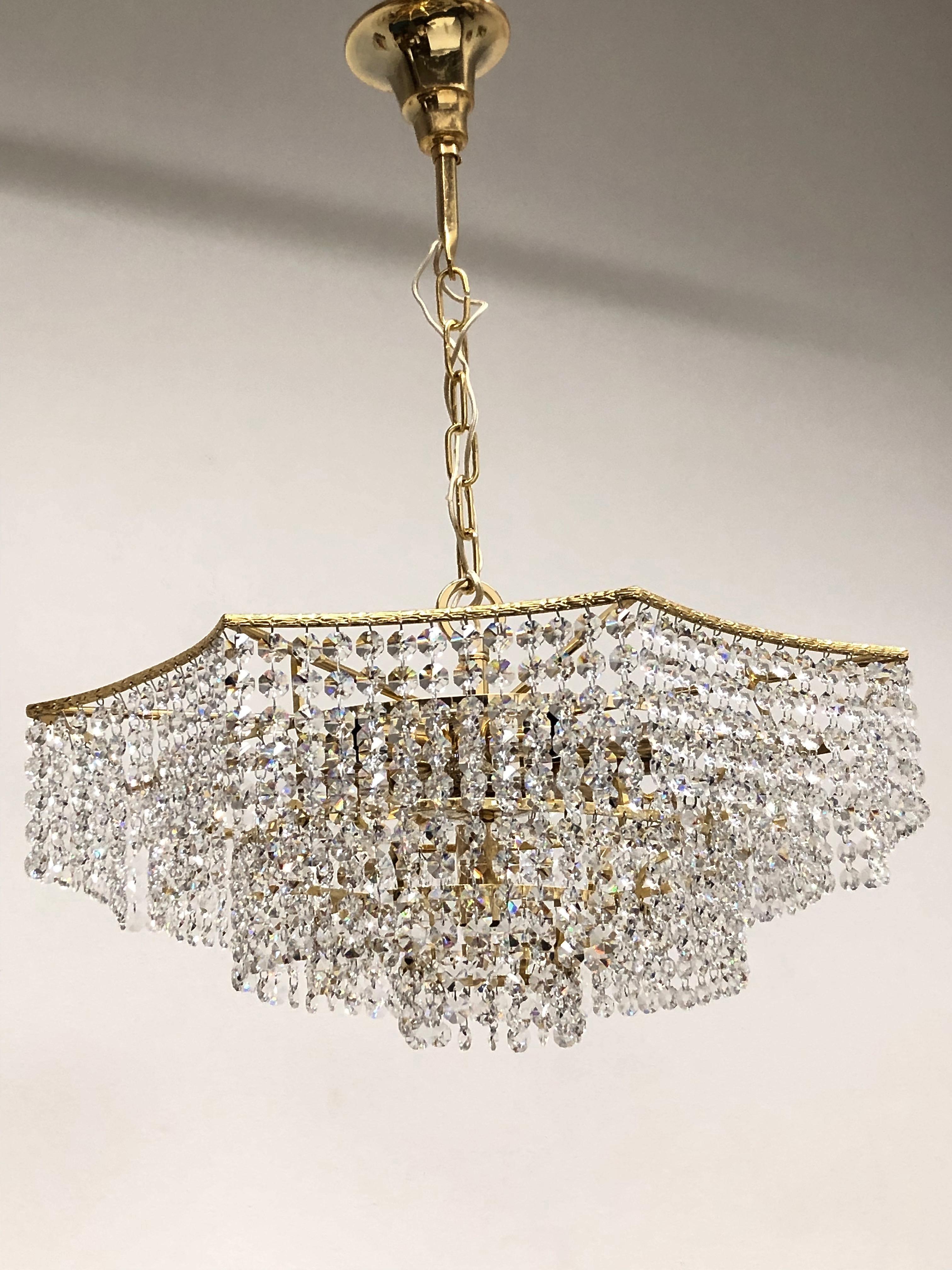 A beautiful 5-tiered brass and crystal glass chandelier made by Richard Essig, Germany, 1960s. The chandelier requires seven European E14 candelabra bulbs, each up to 40 watts. It is made of cut crystals and a brass frame, brass frame is gold