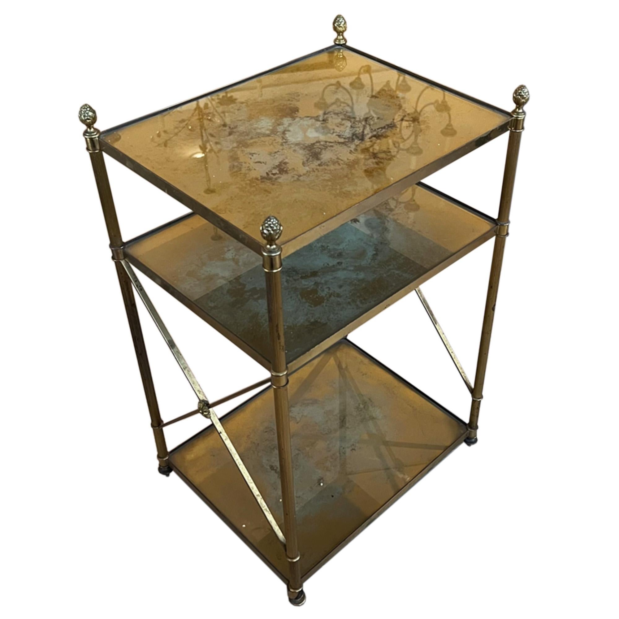 This three tier side table was made in France in the 1960s using brass and eglomise glass. 

The empire style designs on the sides are finished with a flower - please take a look at all our photographs to see this detail and the gorgeous eglomise