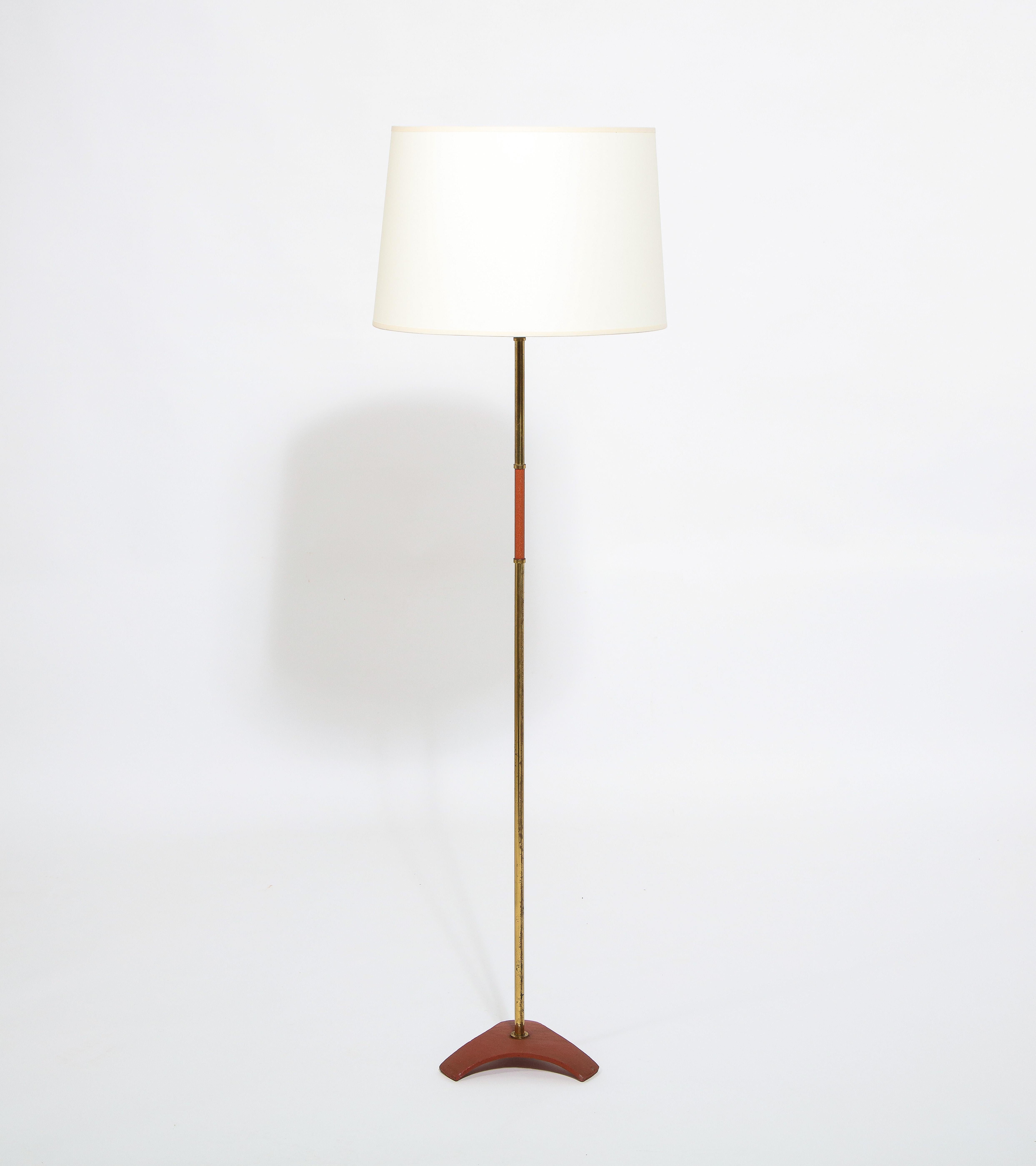 Minimal floor lamp in patinated brass with textured red enamel accents on a domed tripod base. Shade is for photographic purposes.