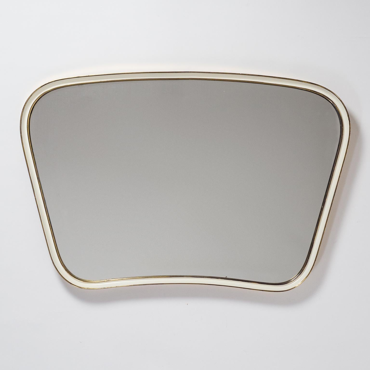 Beautiful midcentury curved brass mirror from 1950s. An unusually thick continuous brass frame which also curves towards the outside and has an off-white enamel coating on the inlet. Very nice original condition with patina on the brass and some