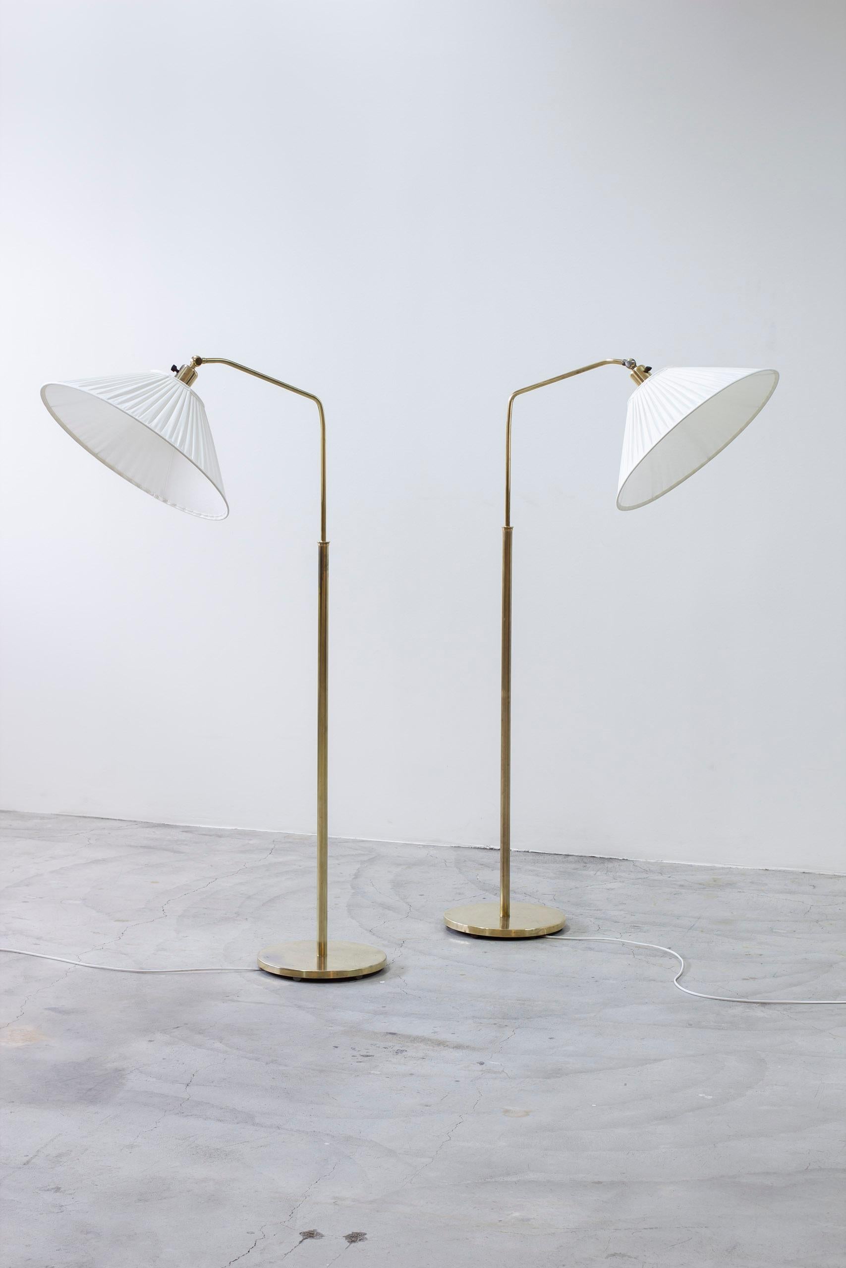 Pair of floor lamps model 15028 designed by Harald Elof Notini. Produced in Sweden by Arvid Böhlmarks Lampfabrik during the 1940s. Made from brass with newly produced lamp shades with off white chintz fabric, sewn with single hand pleating. Bakelite