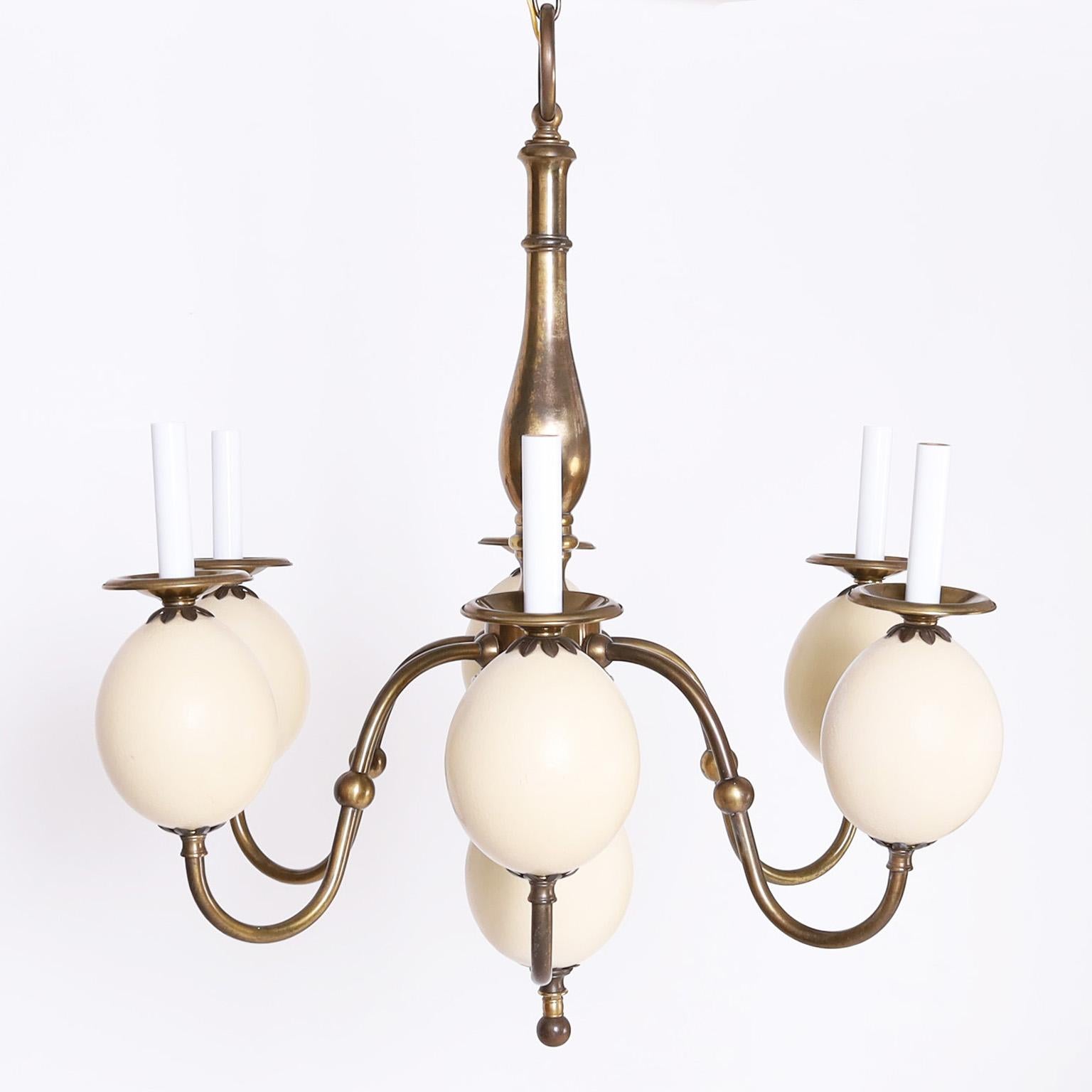 Attributed to Redmile, a chic six light chandelier crafted with brass in a classic Queen Anne form enhanced by faux ostrich eggs as bobeche supports and bottom finial.
