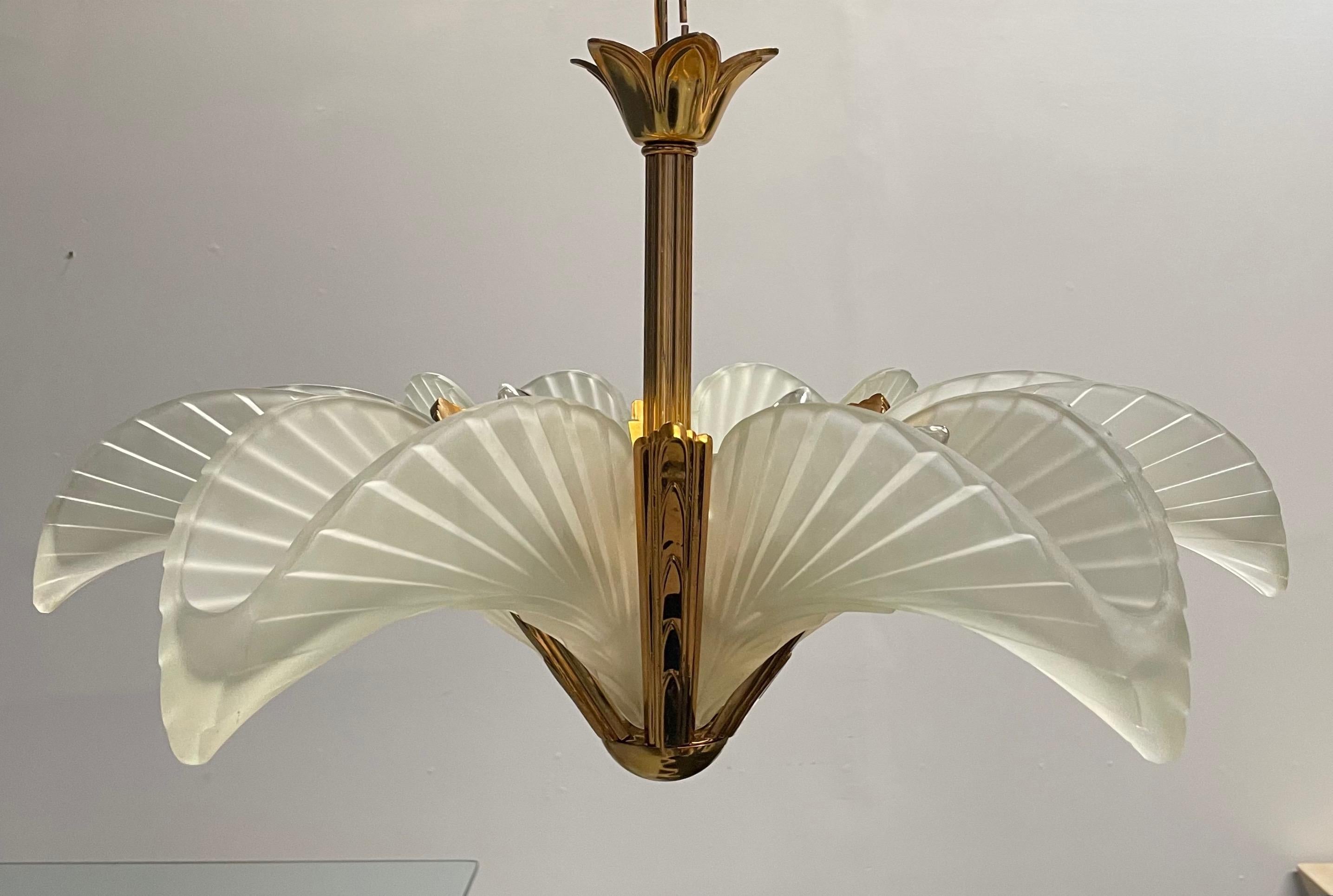 This stunning high quality fixture is from the early 1980s and created in a Classic Art Deco form. It features solid brass frames, thick frosted glass shades, and take 5 standard bulbs. It also includes it's original brass hanging chain and ceiling