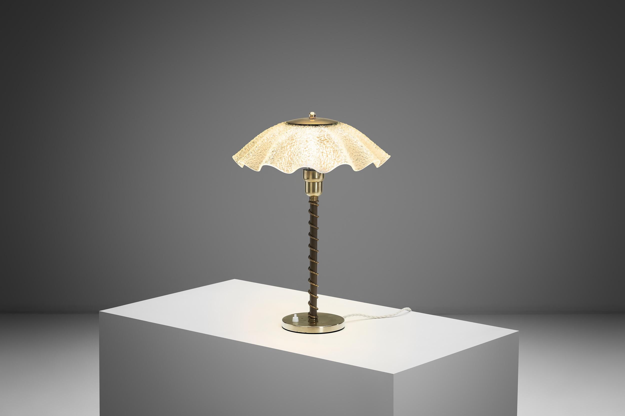 This Danish brass and frosted glass table lamp, dating back to the 1940s, reflects the elegance and refinement of early modern Scandinavian lighting design. In the period between Art Deco and the rise of mid-century modernism, Danish designers were